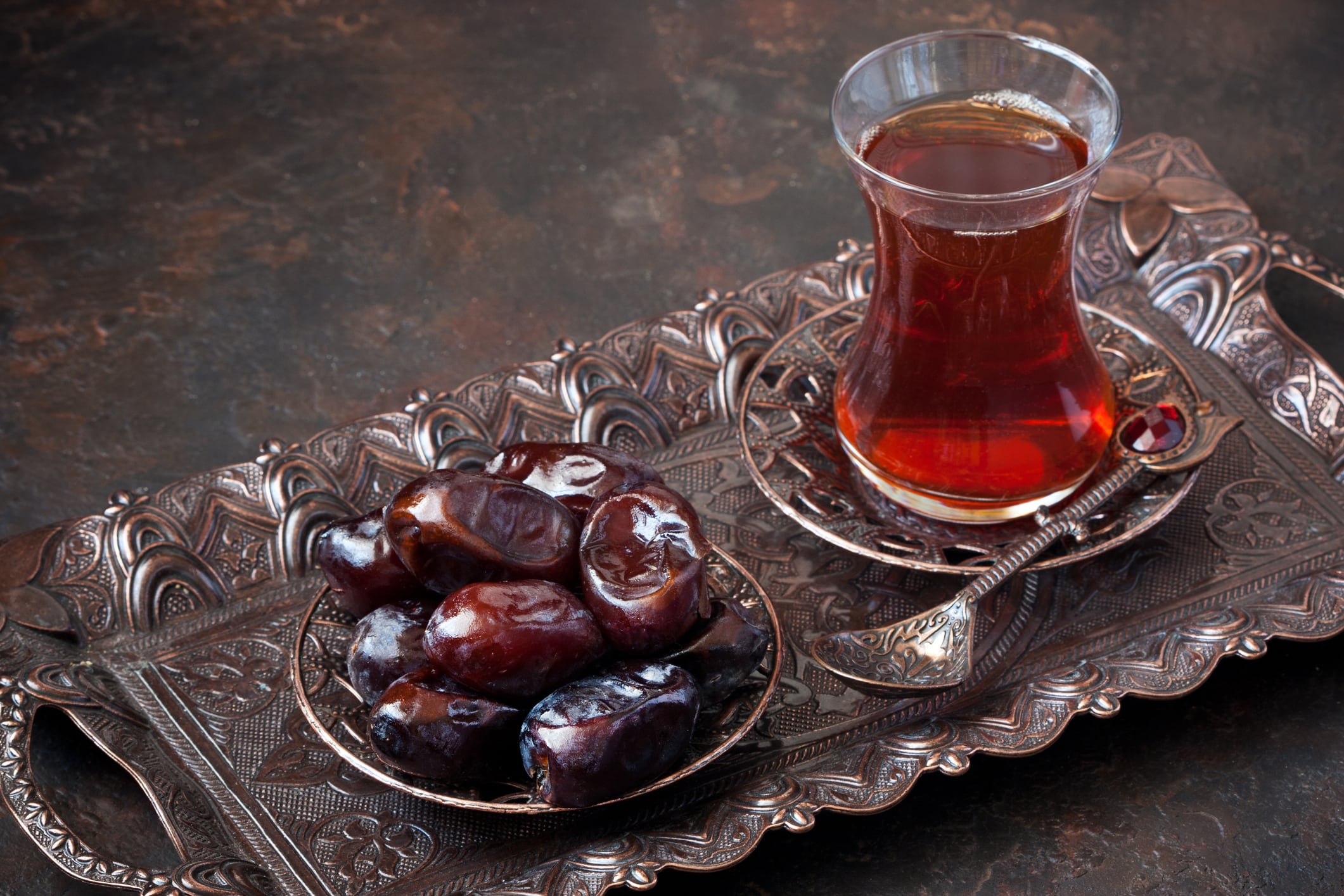 Turkish tea in glass cup with date fruit in traditional copper serving set