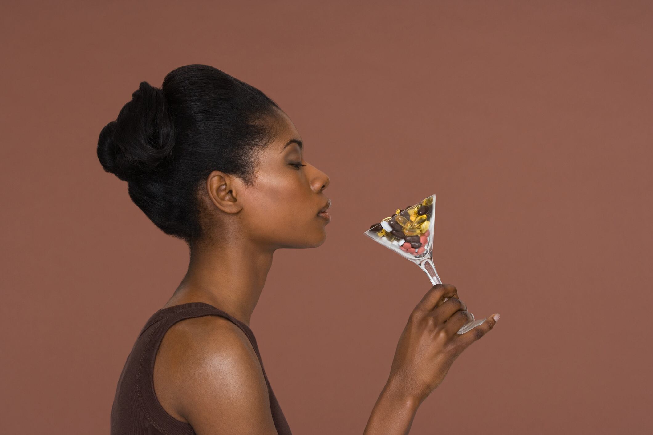 Young woman holding a cocktail glass of vitamins