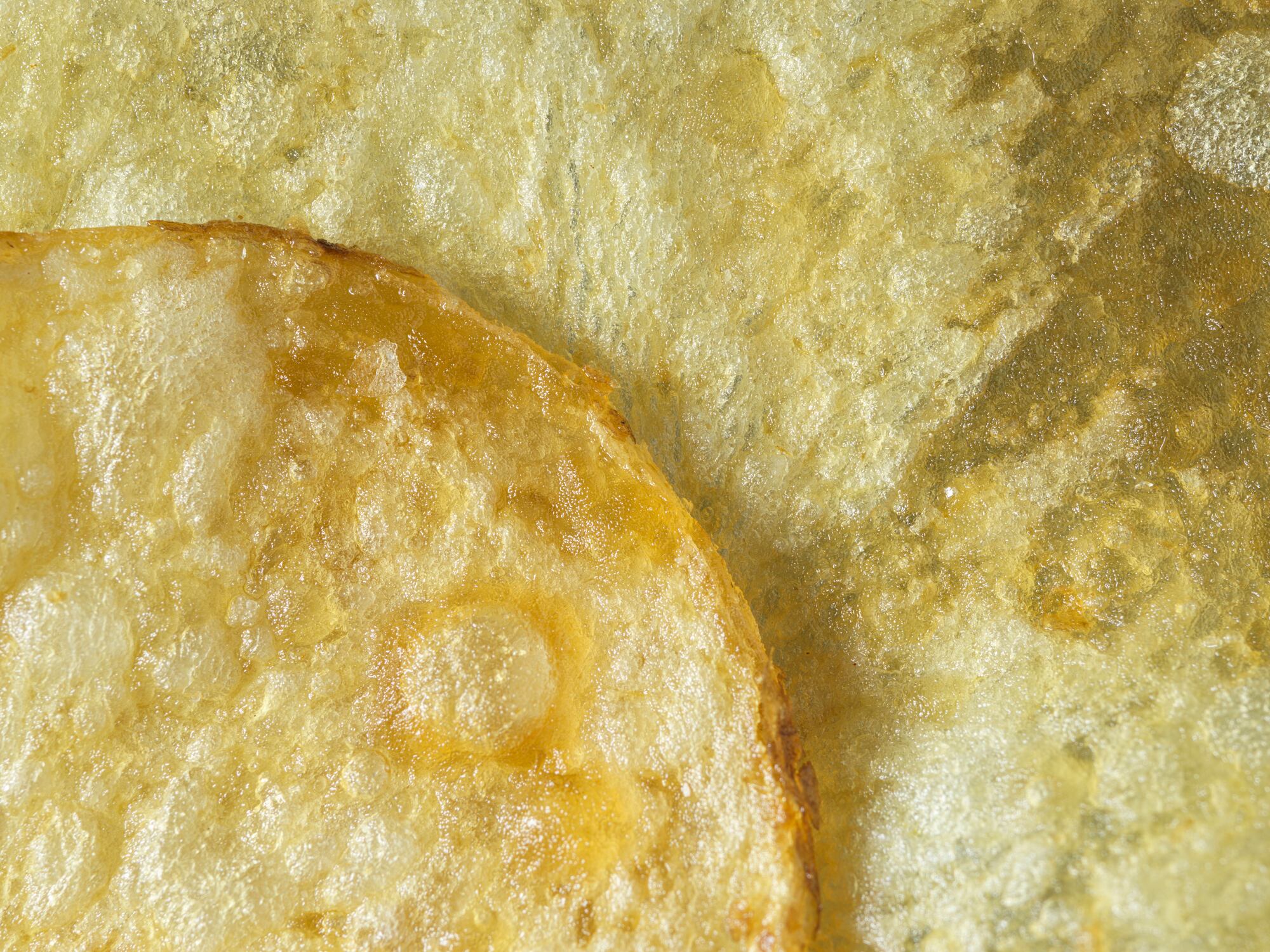Extreme close up textured, rounded edge of potato chip