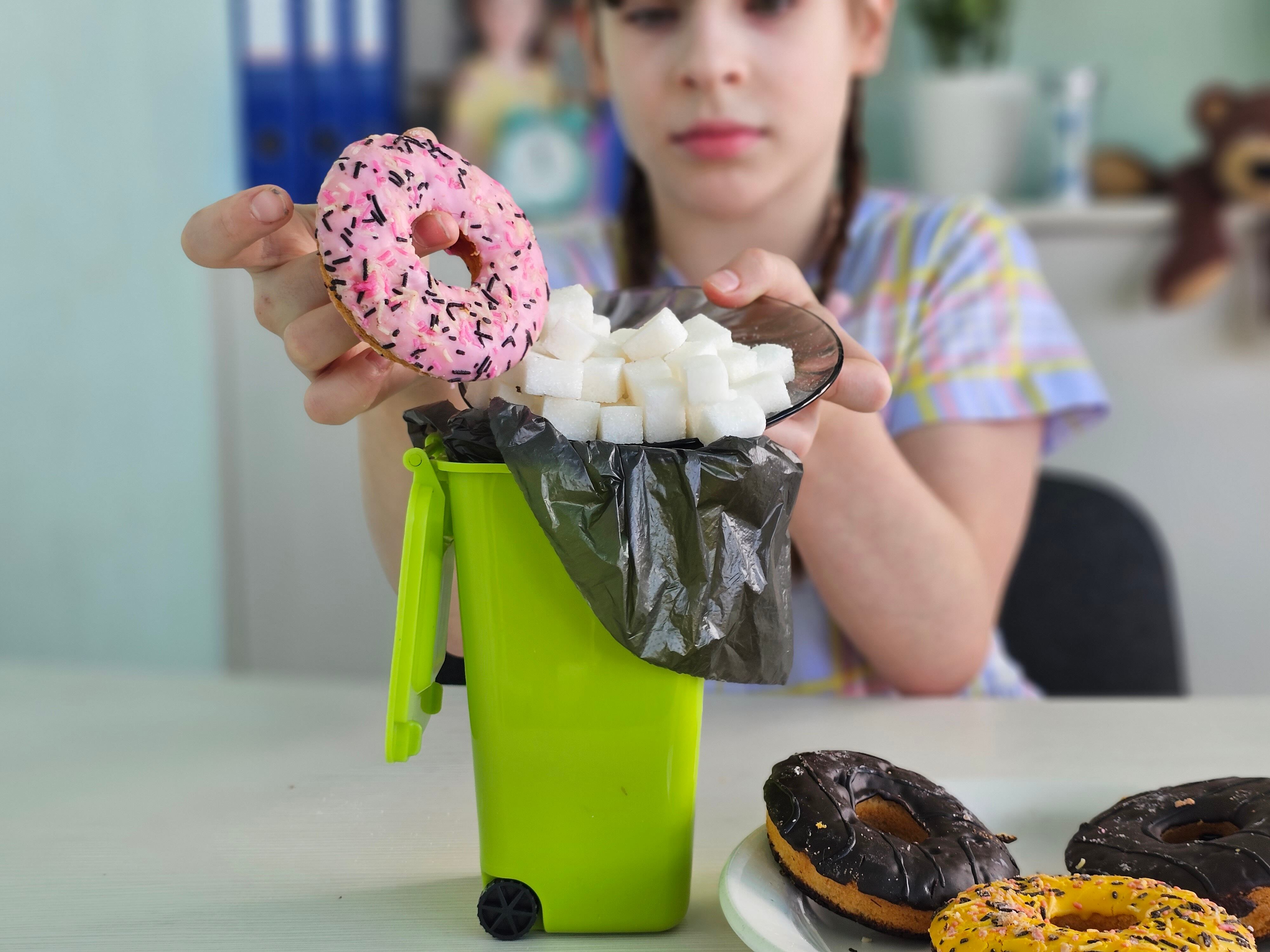 Child throwing high-sugar doughnut in the bin