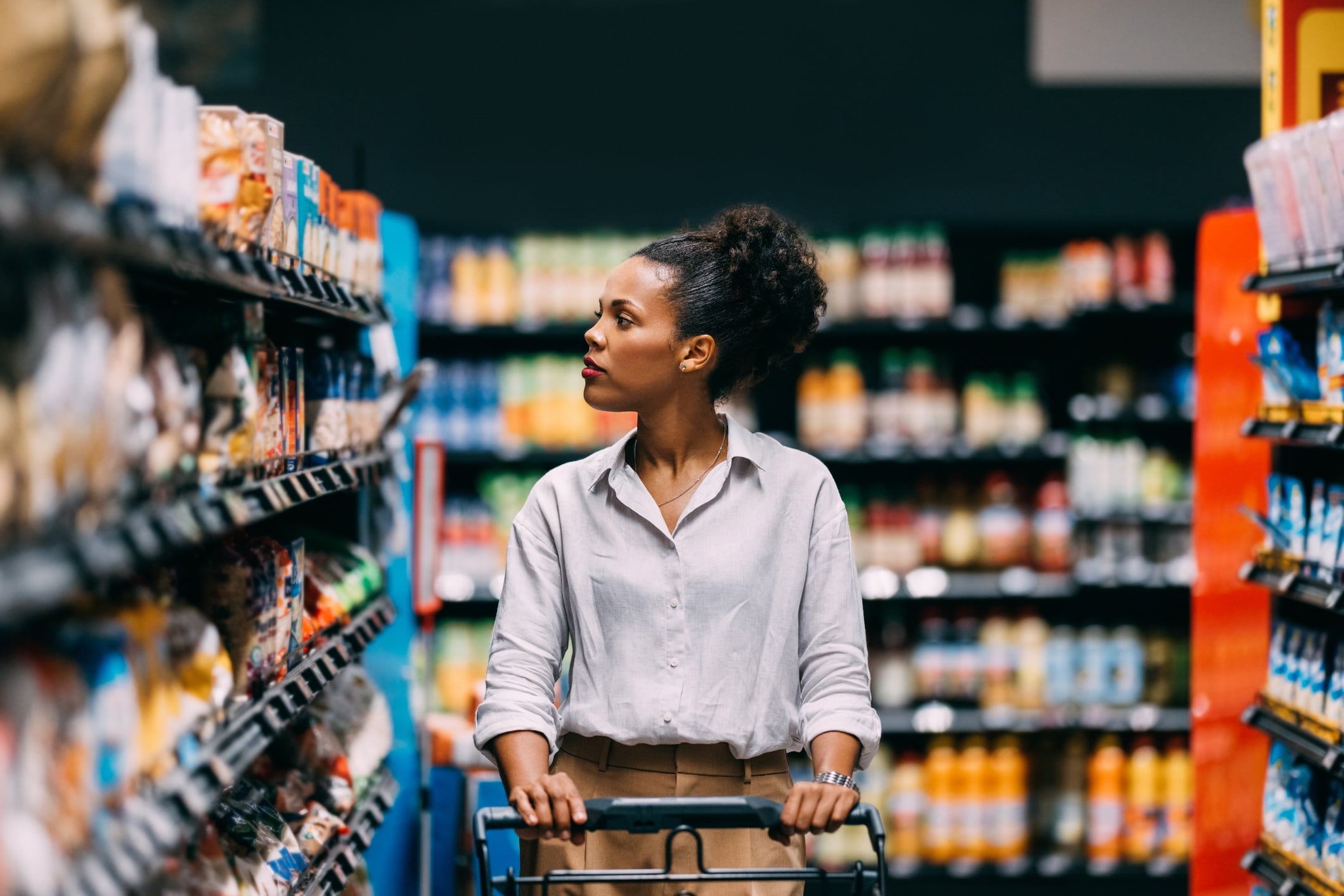 Female pushing a shopping trolley while choosing merchandise at the grocery store.