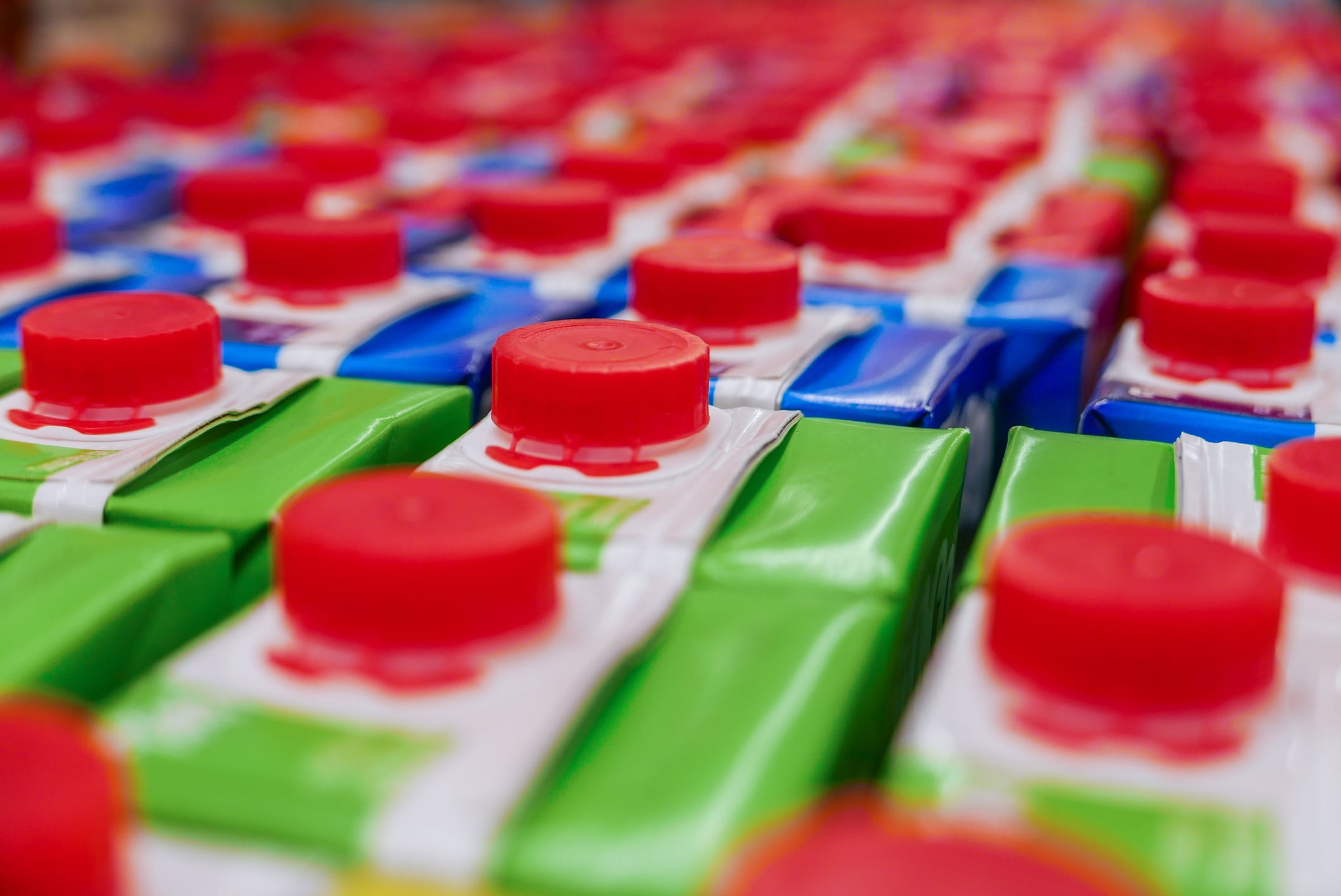 Juice cartons with red screw cap in supermarket shelf.