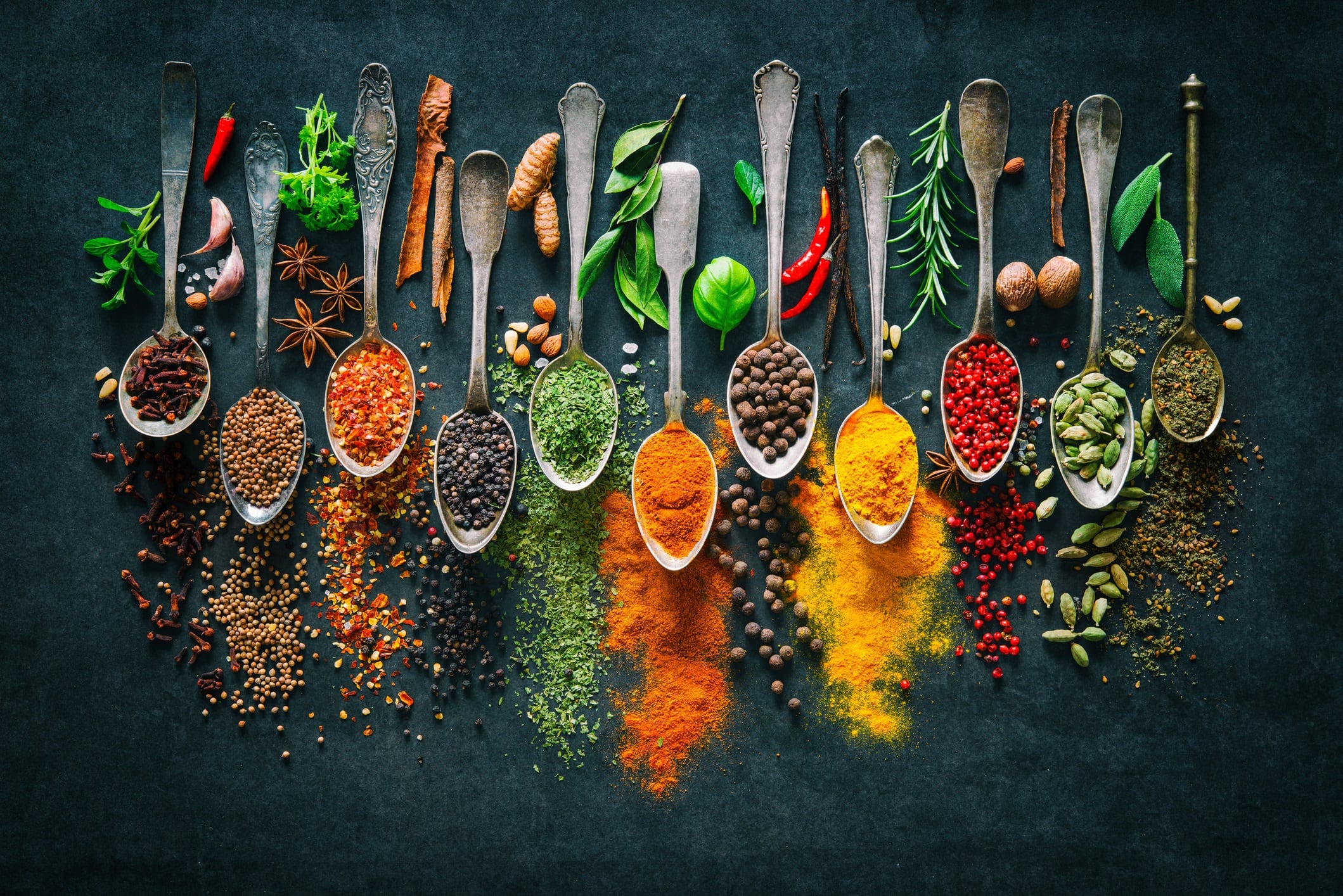 Colourful various herbs and spices for cooking on dark background.