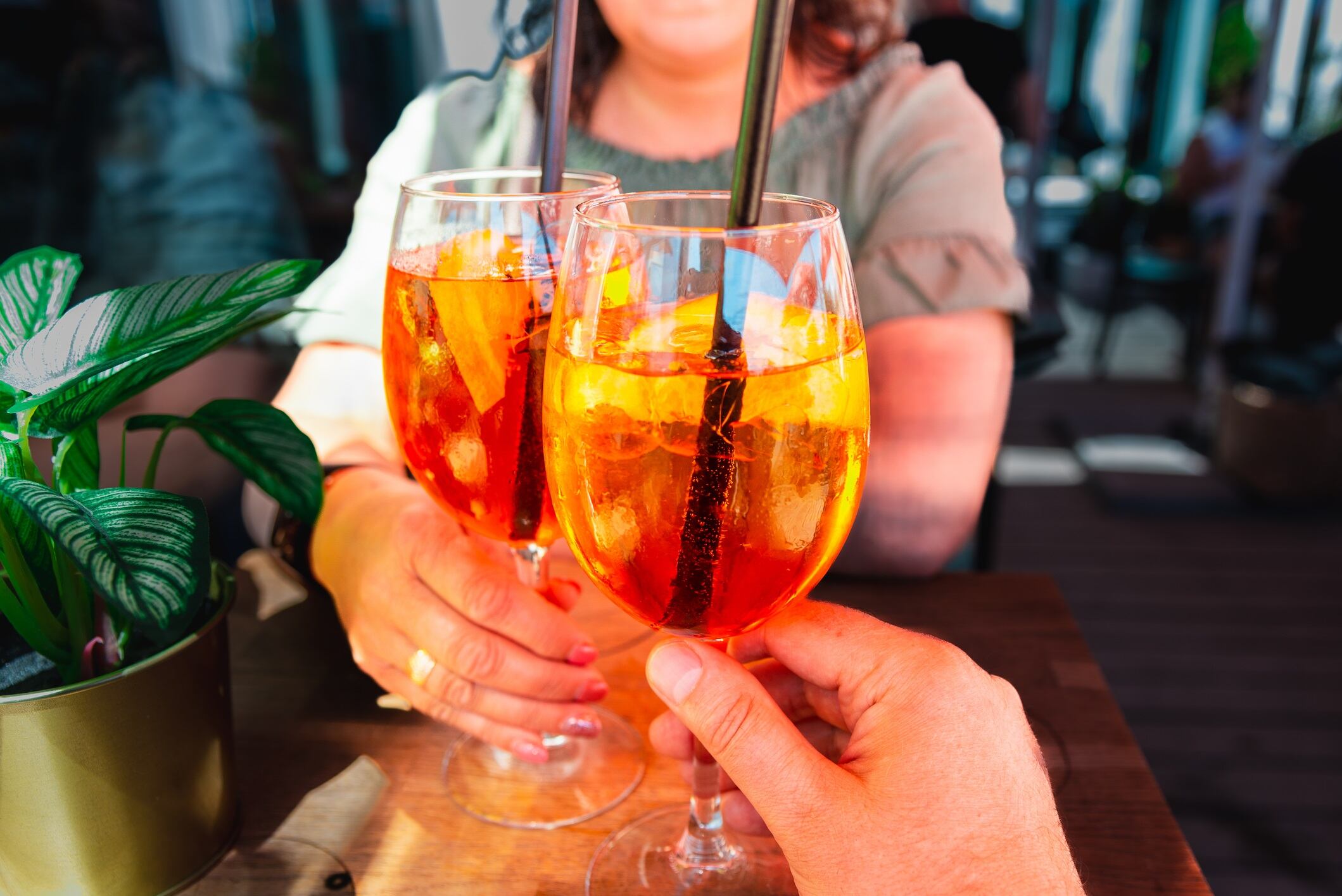 Couple celebratory toast with Spritz orange alcoholic cocktails at outdoors cocktail bar at night. Close up.