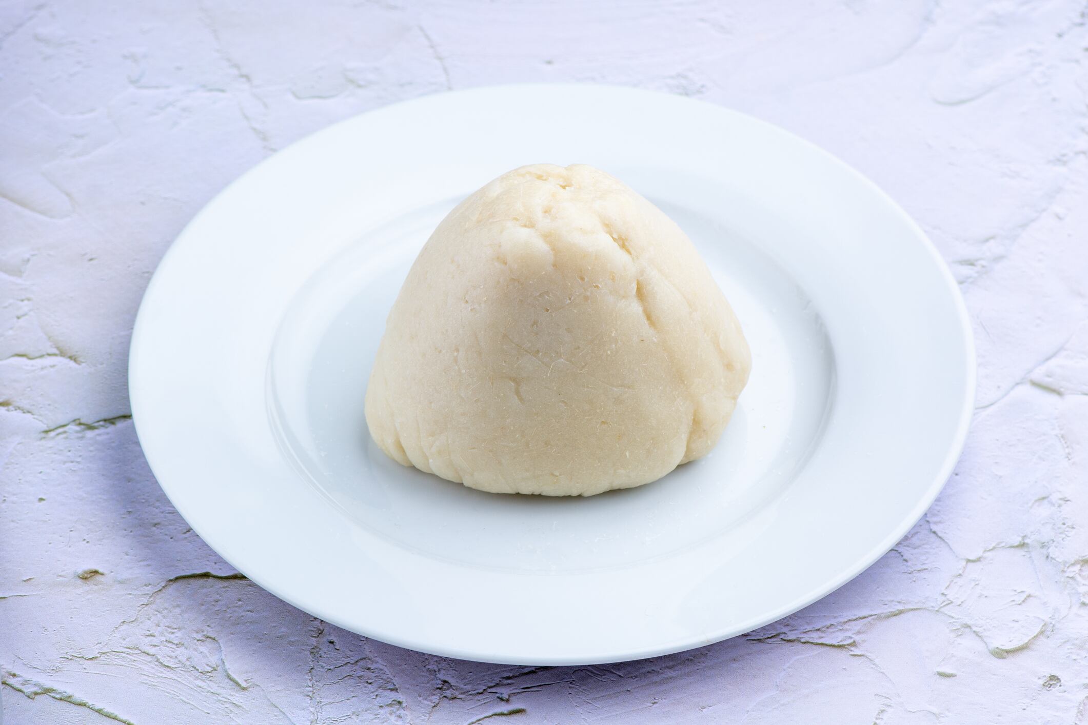 An image of fufu / pounded yam isolated on a white, ceramic plate