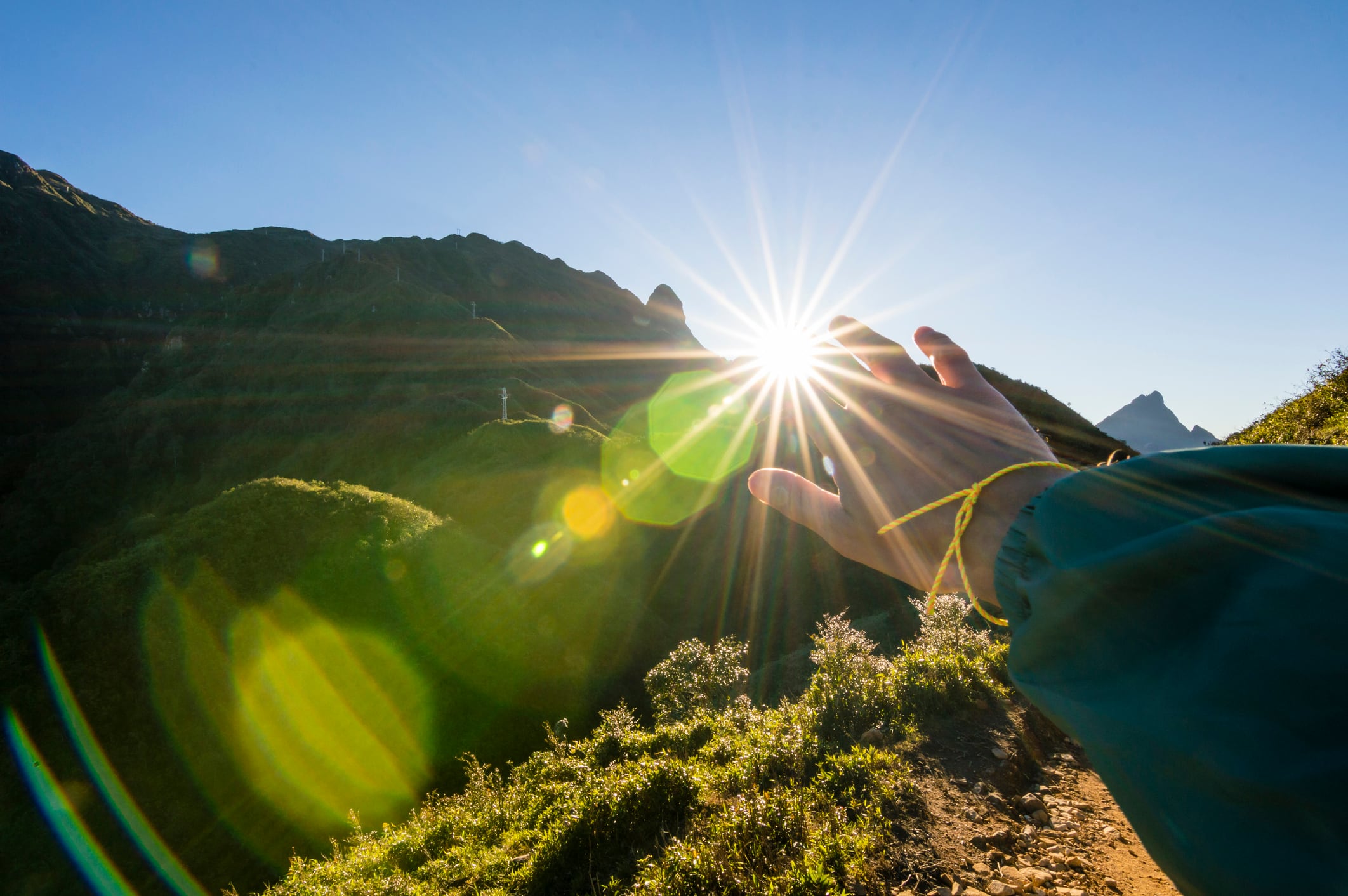 Young woman hikes up mountain slope, sunrise