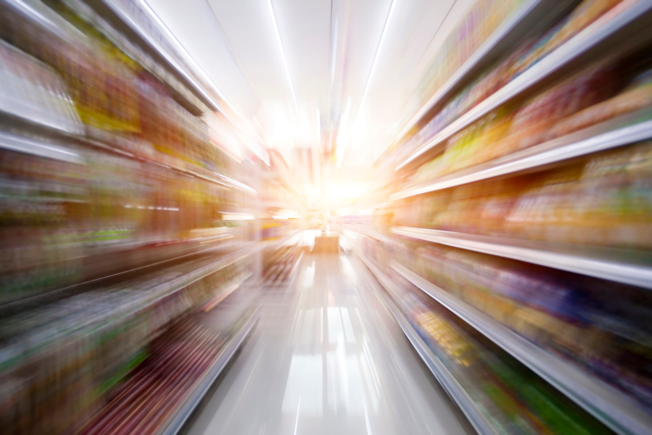 Supermarket aisle with bright light at the end.