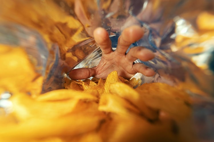 hand taking crisps from bag
