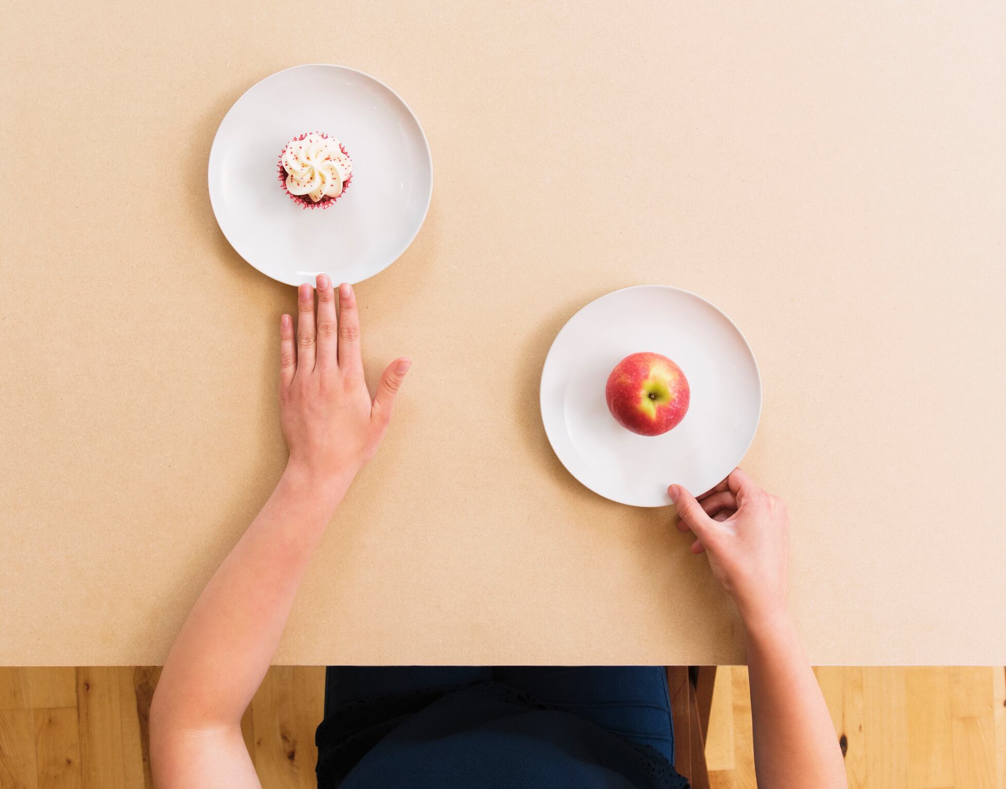 Caucasian woman choosing apple instead of cupcake at table