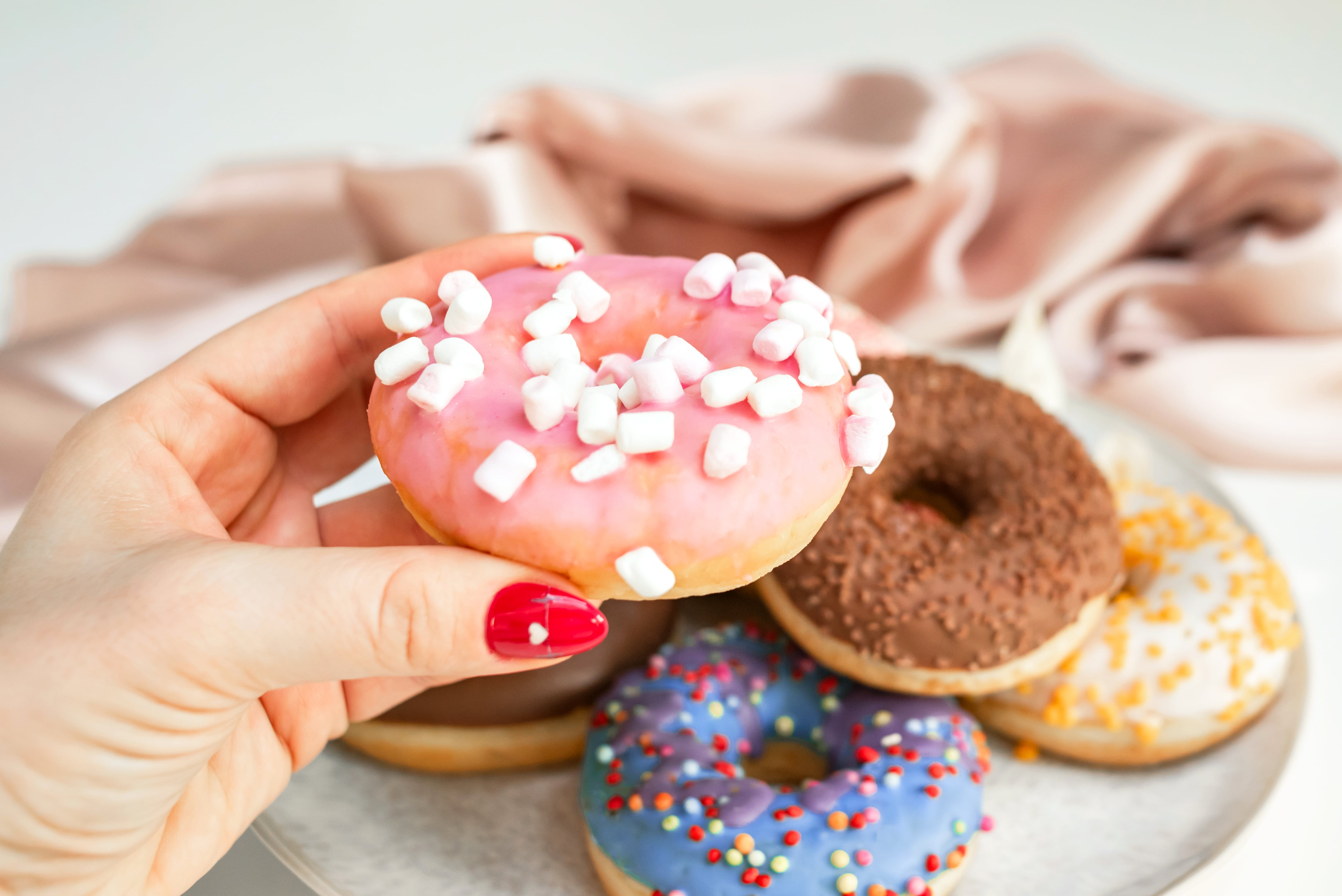 Hand with tasty donuts on color background, Hand takes a donut from a plate