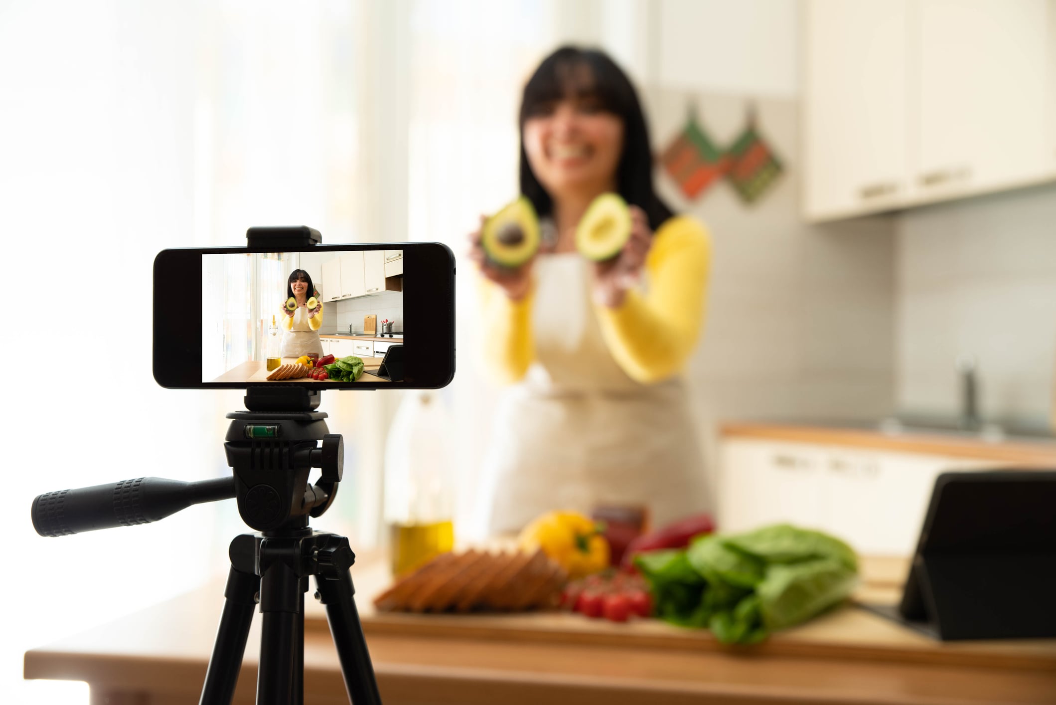 Woman cooking healthy food in the kitchen - Food blogger recording video tutorial at home - People, food and blogger concept