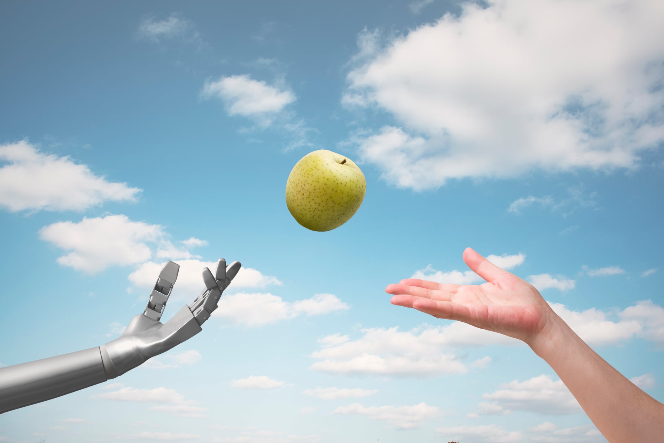 Human hand passing apple to robot hand, blue sky in the background