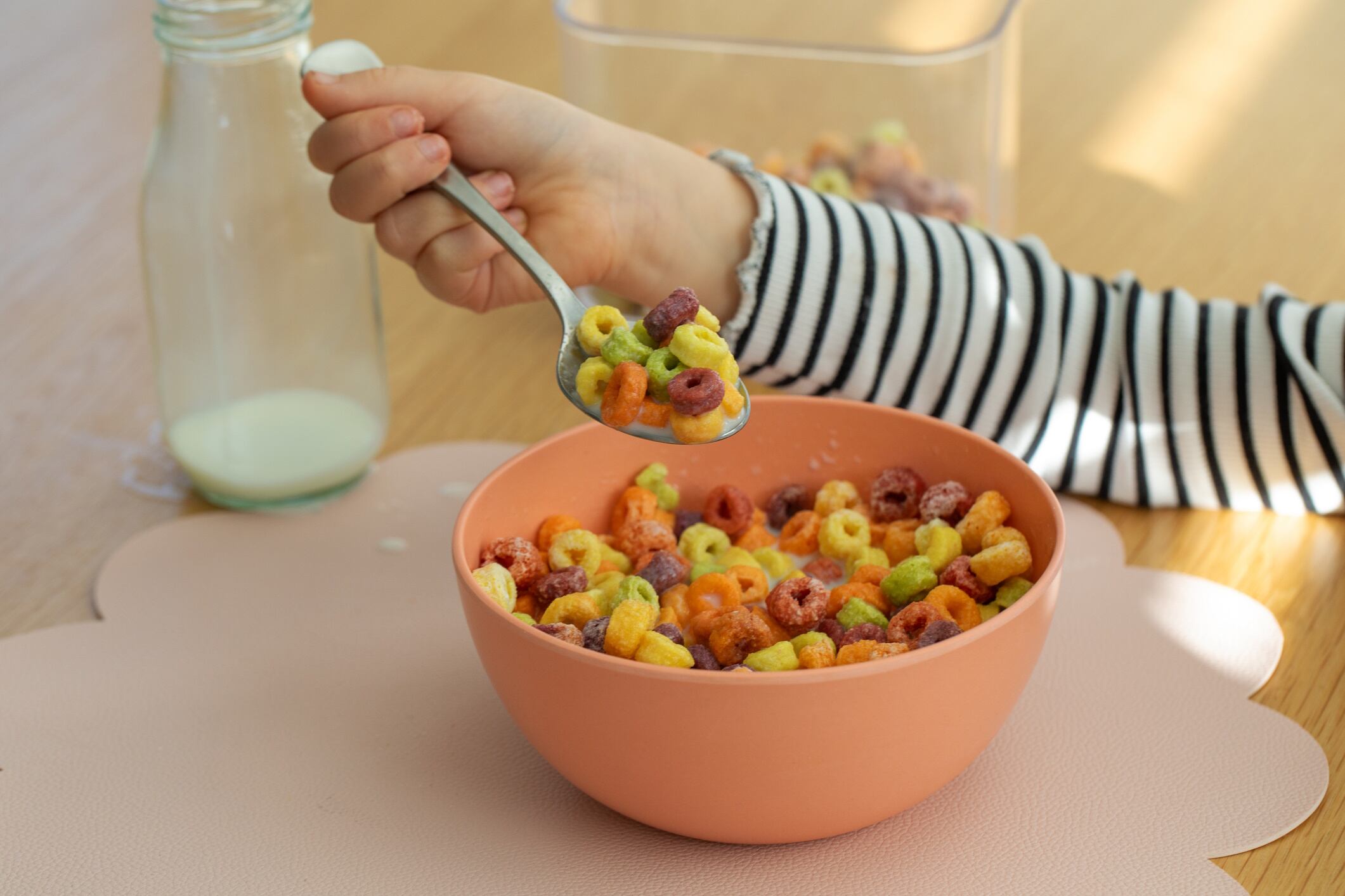 Child enjoying colorful cereal with milk at breakfast table