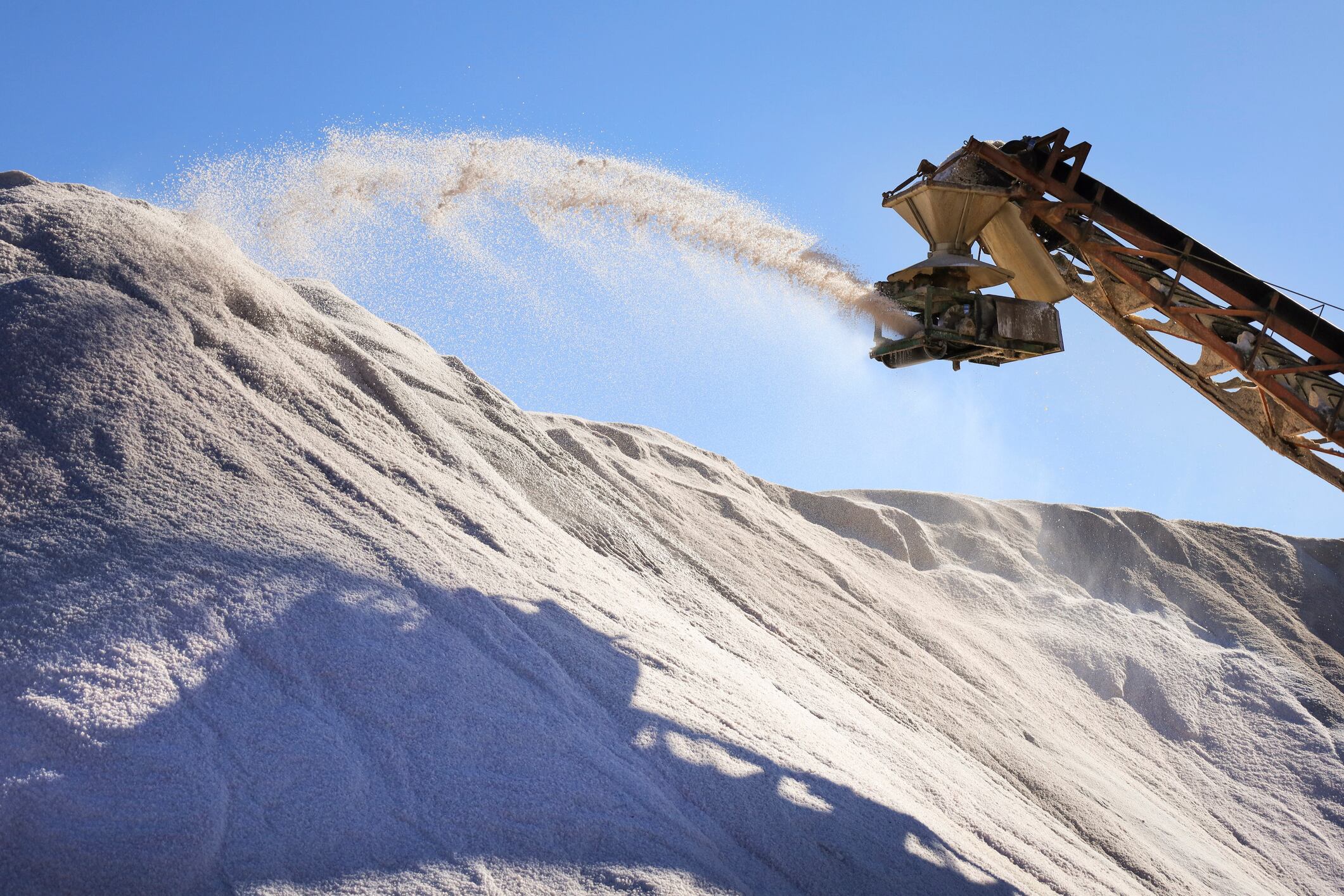 Harvester throwing salt in the Mountain of salt in the Saltworks in the natural park of Santa Pola town, Alicante, Spain