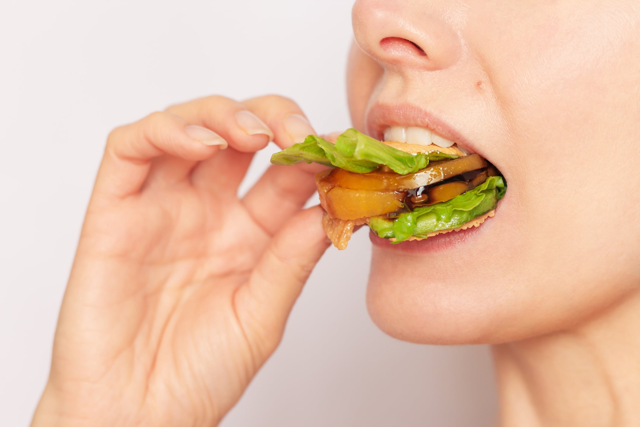 Close-up of the face of a young Caucasian vegan woman eating a healthy vegetable sandwich, observing proper nutrition, watching her health.