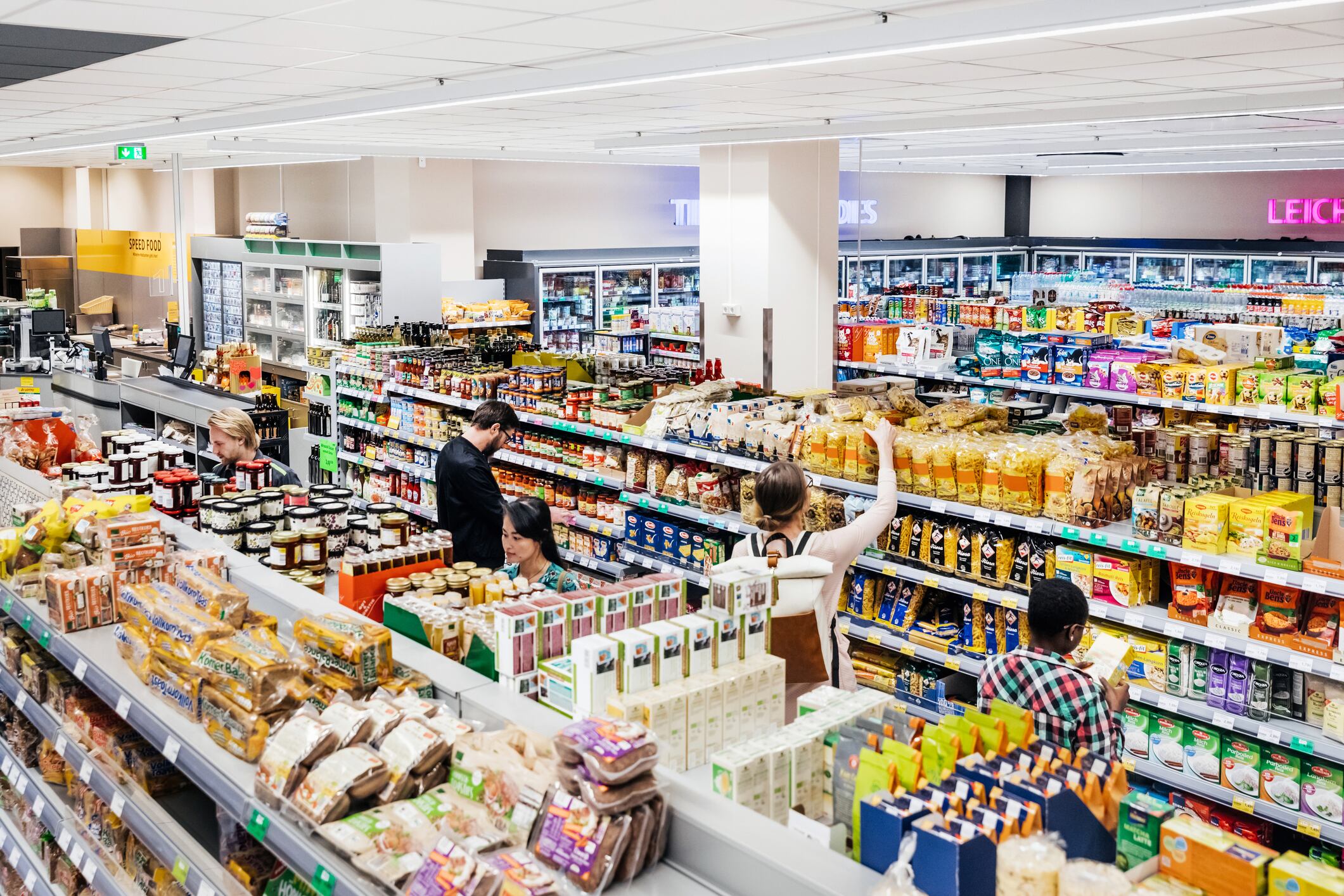 A busy and colorful supermarket with customers shopping for groceries.