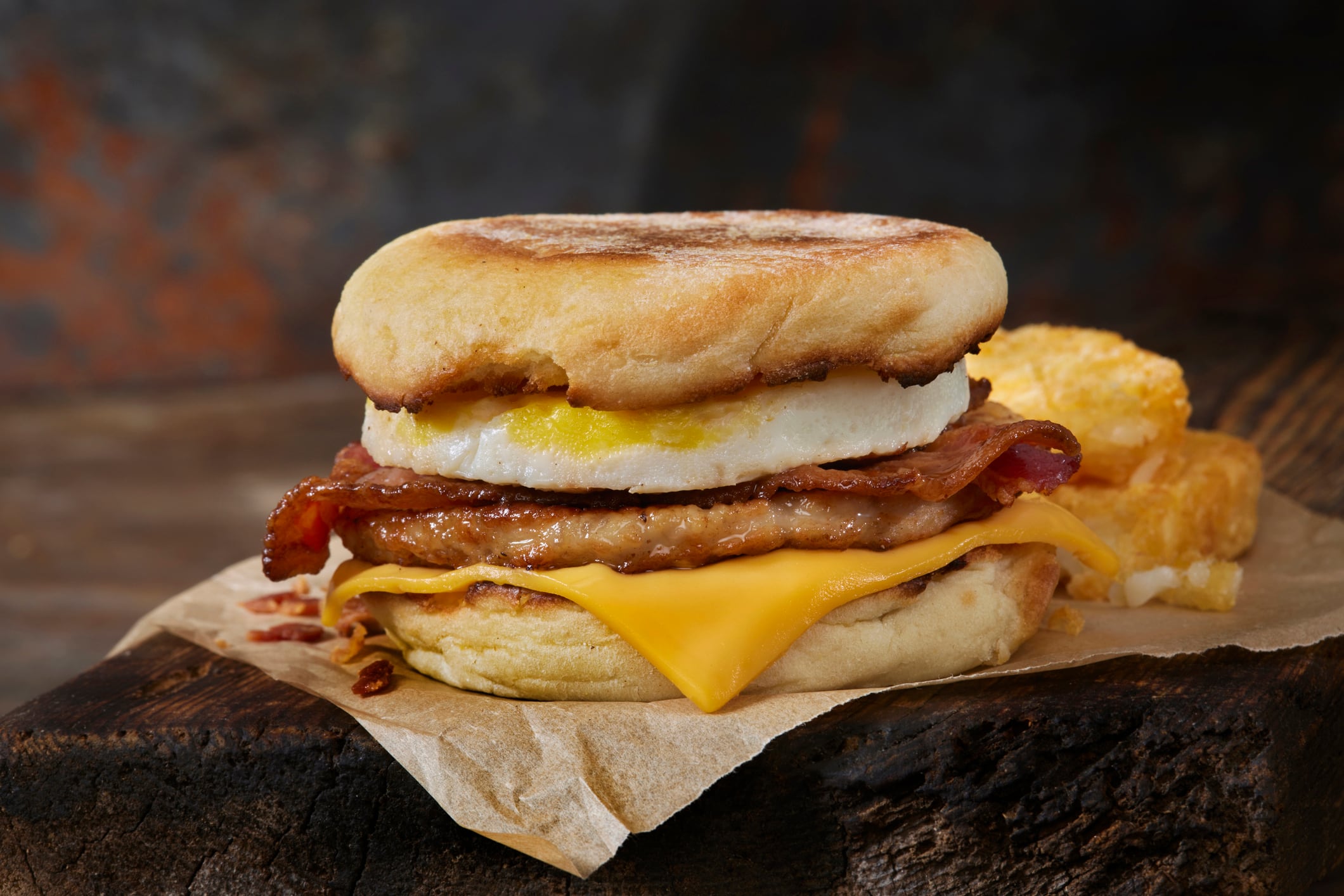 Bacon, sausage, egg and cheese breakfast sandwich on an English muffin.