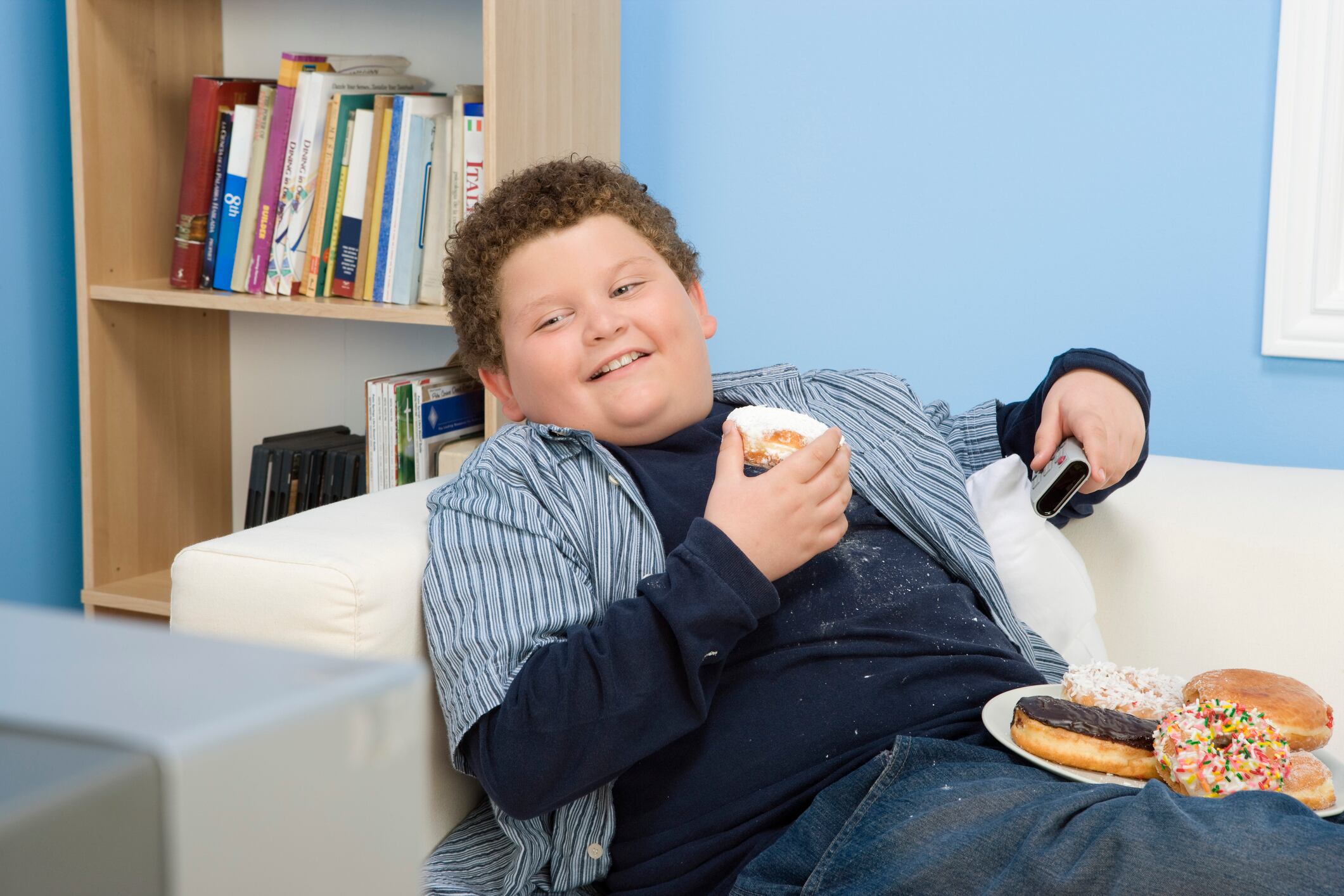 Child watching TV with doughnuts and snacks.