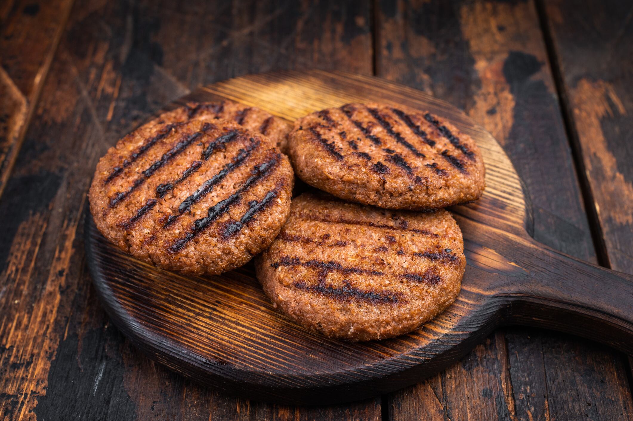 Vegetarian grilled burger patties plant based meat substitute high protein cruelty free food rustic dark background.