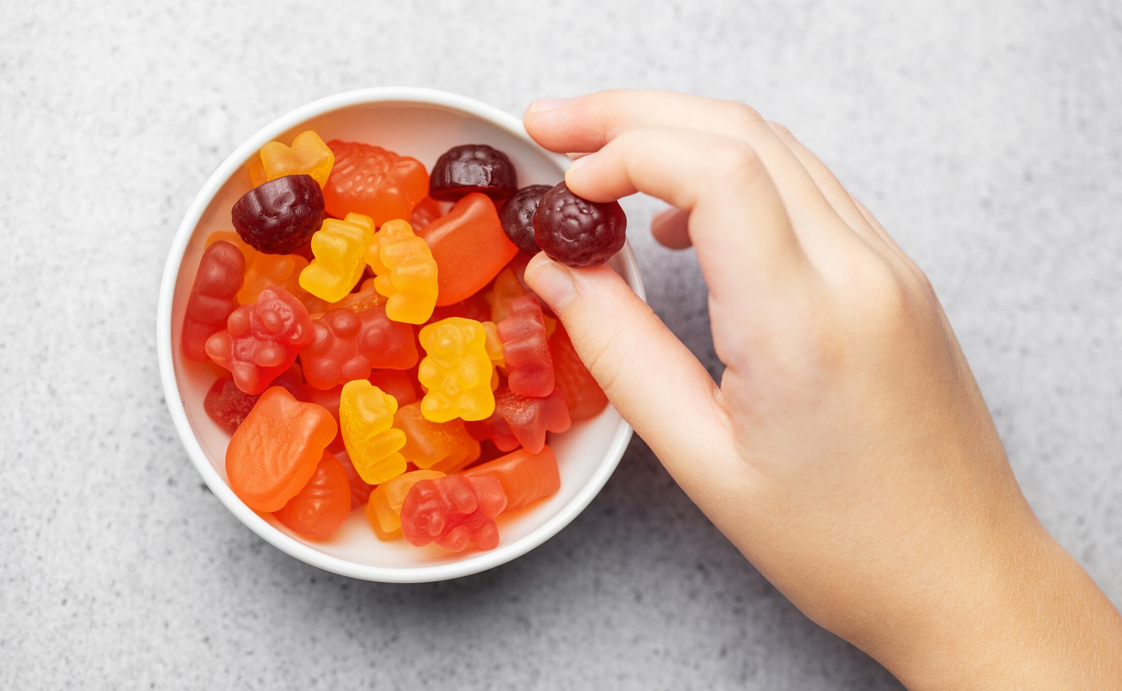 Chewable gummy bears vitamins and supplements. A girl holds a gummy bear vitamins in her hands.