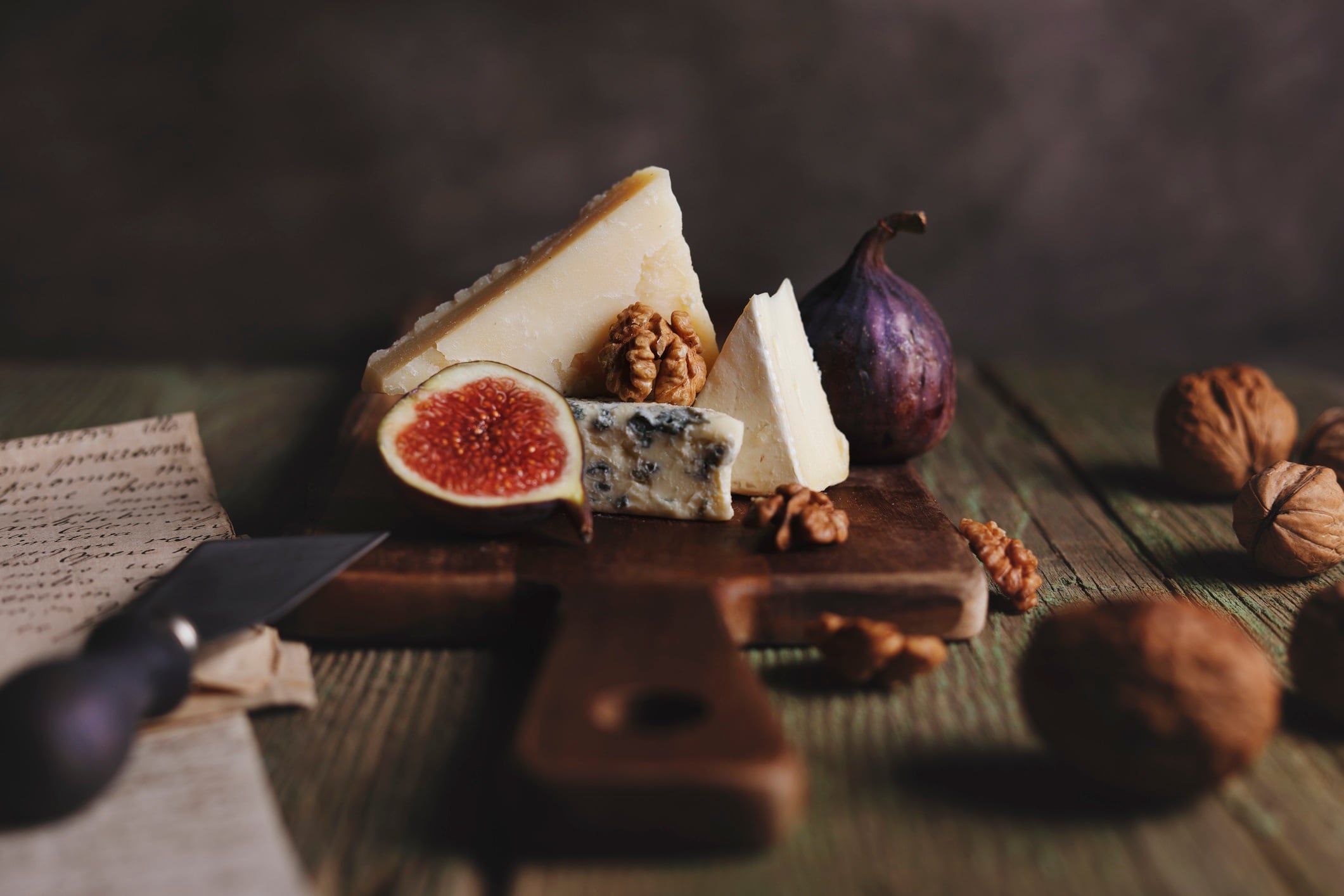 Different cheeses with fig and walnut on a rustic  cutting board