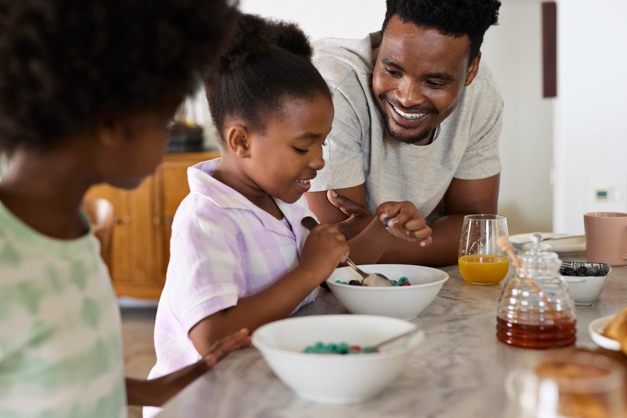 Man sitting next to daughter eating breakfast