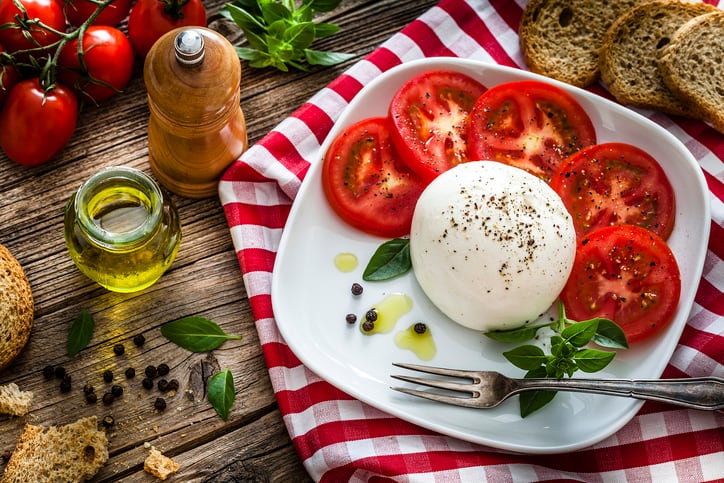 Healthy fresh burrata cheese salad on rustic wooden table