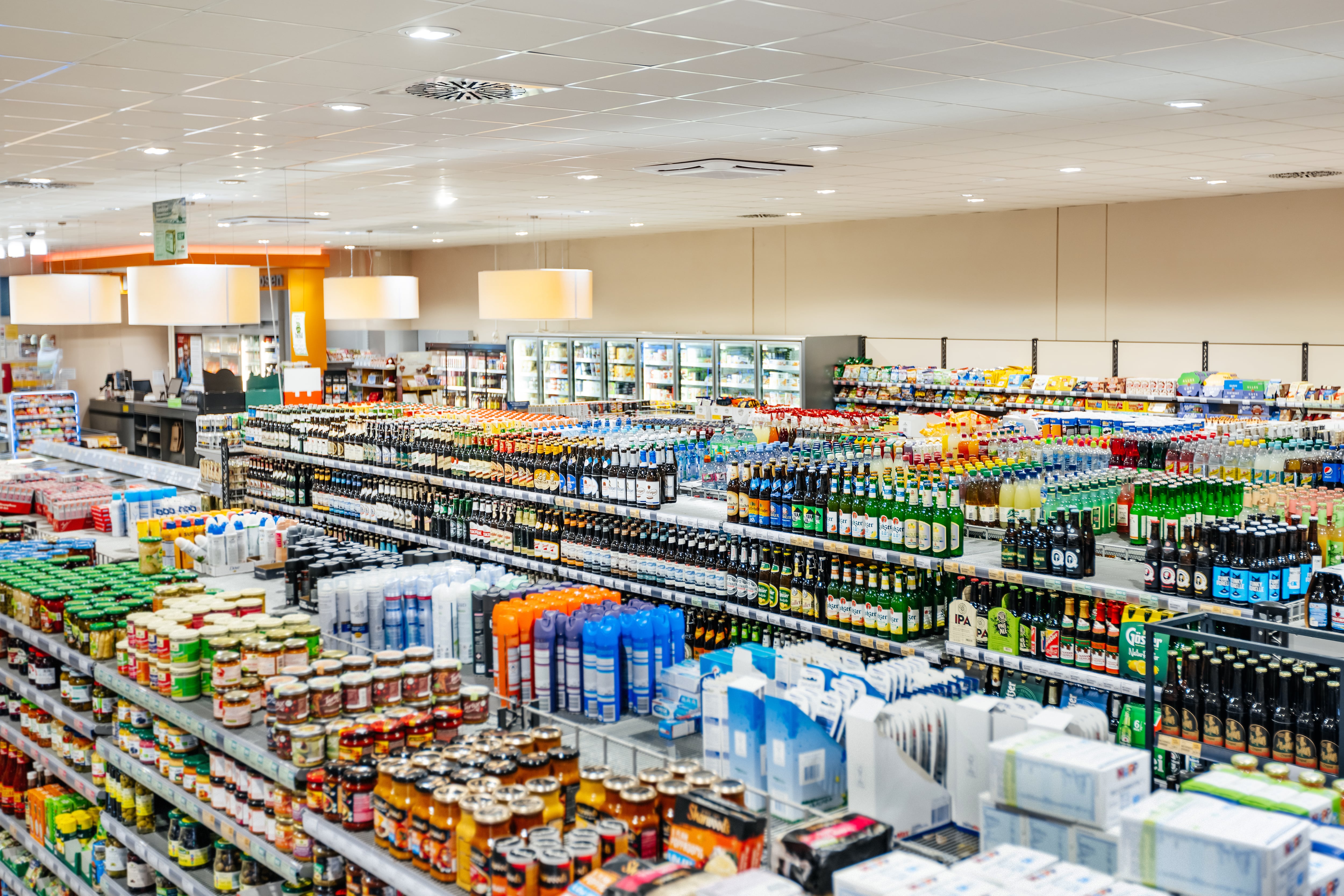 A variety of different food and bottled produce on display in an organised and well stocked, modern supermarket with no customers.