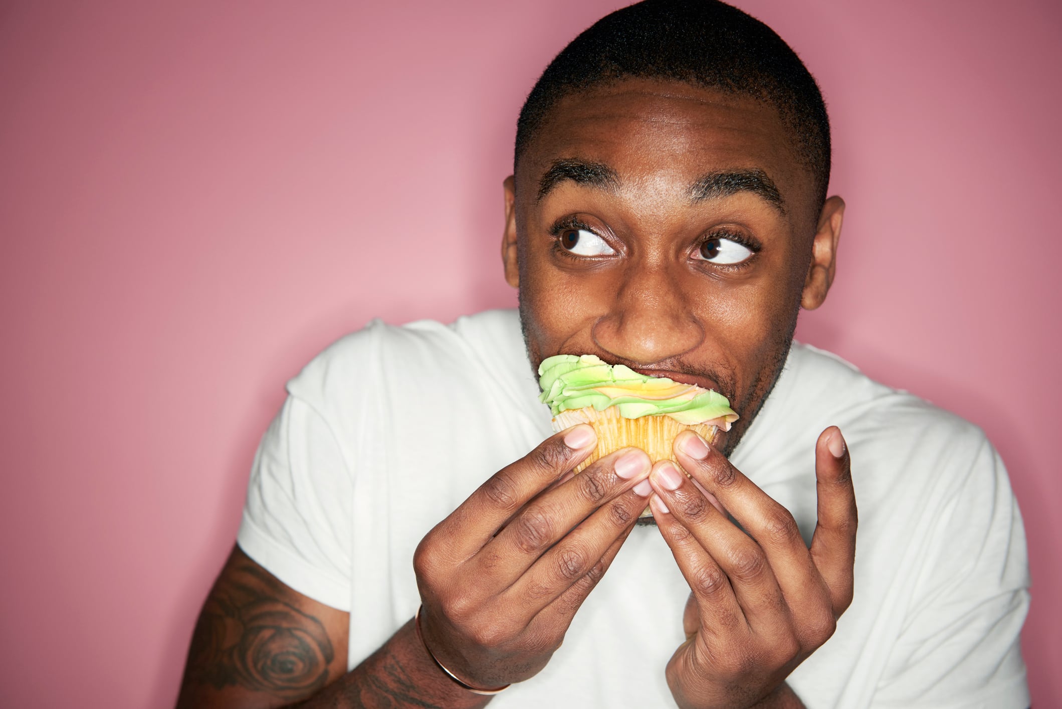 Man eating a cupcake with green frosting