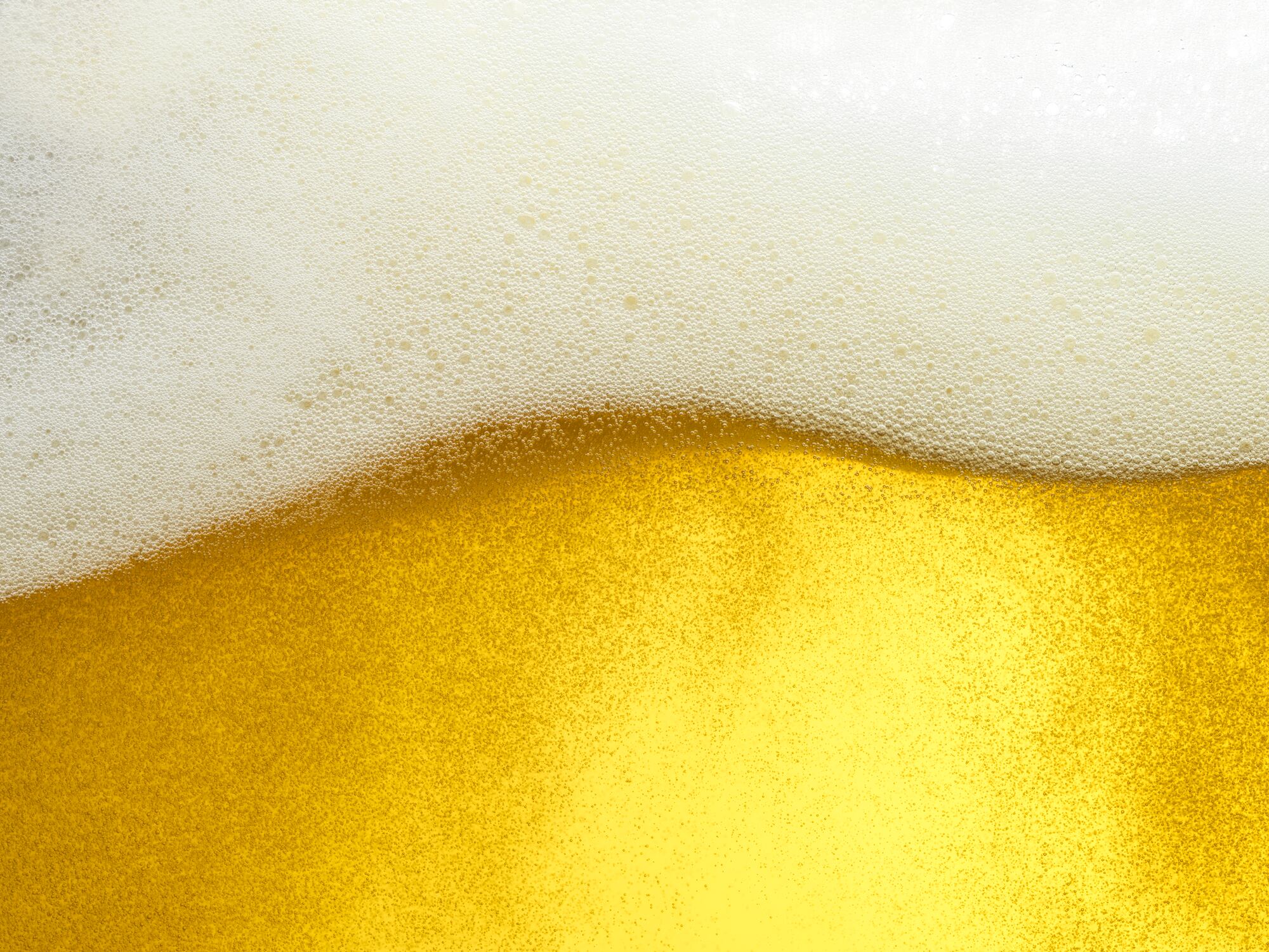 Macro shot foamy golden beer head forming wave pattern