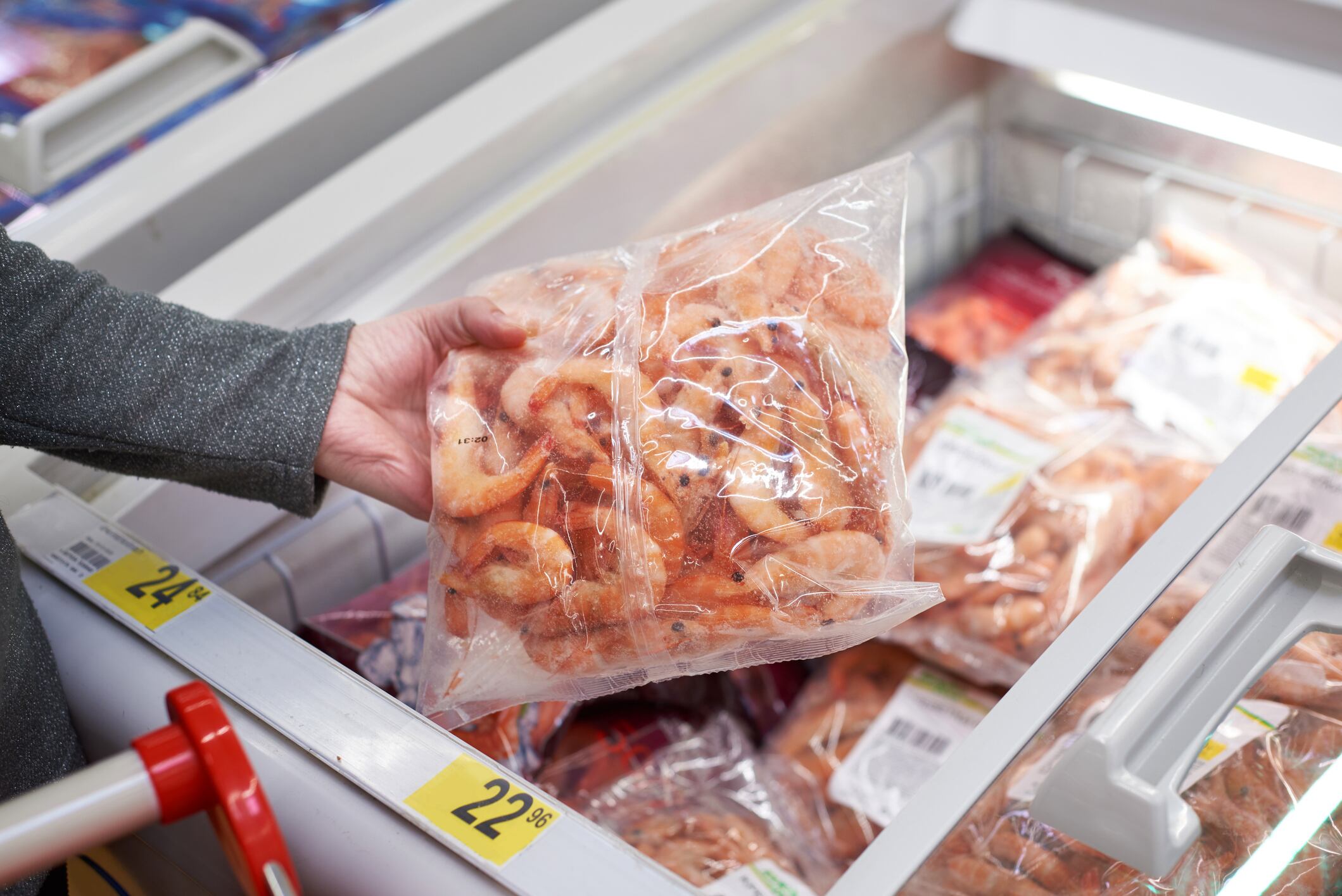 Packing of frozen shrimp in the buyers hand in the grocery store
