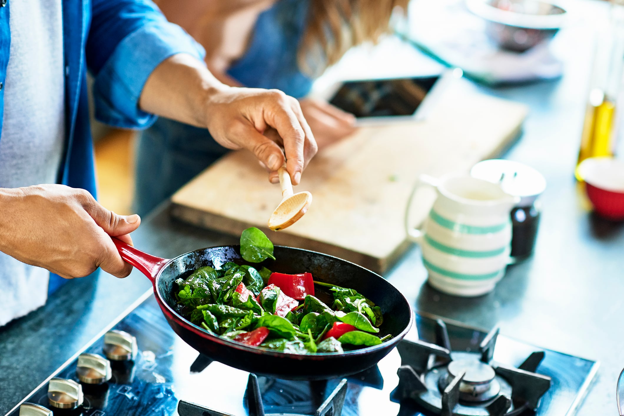 Man frying vegetables, including spinach