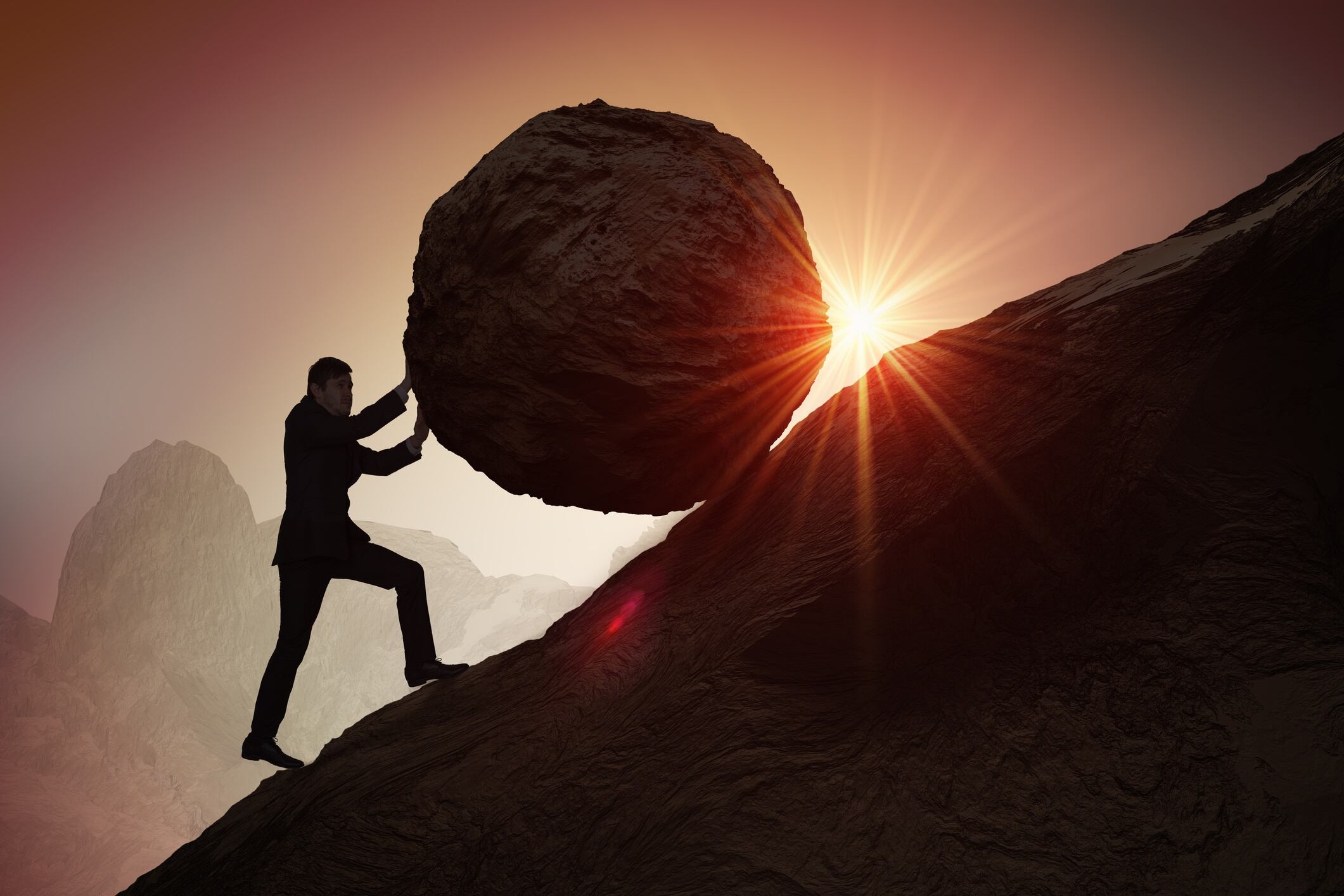 Businessman pushing boulder up hill
