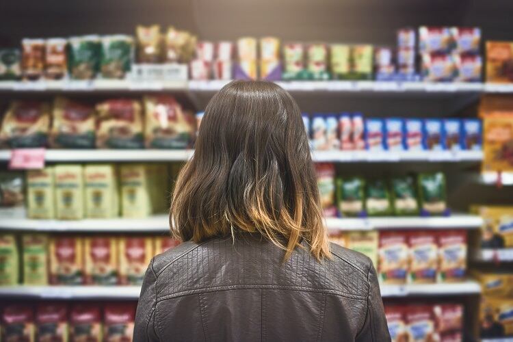 Woman standing in supermarket aisle.