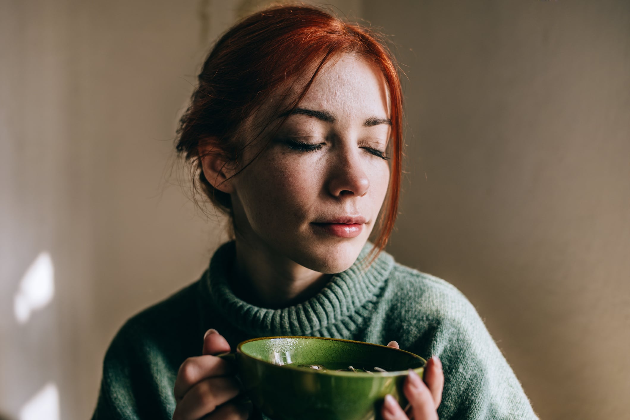 Woman drinking green tea out of a green cup.
