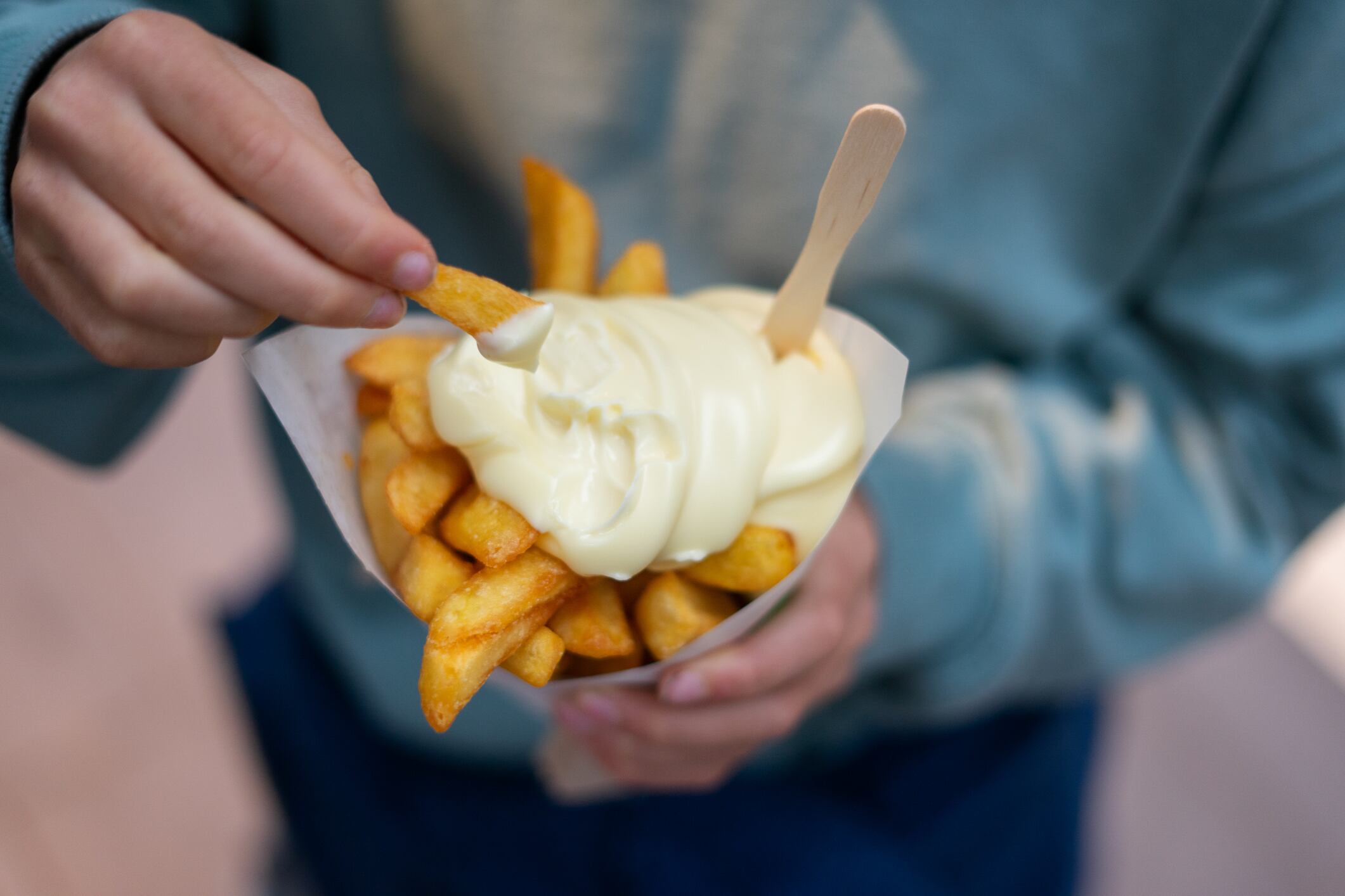 Child enjoying a cone of french fries dipped in mayonnaise, a popular street food