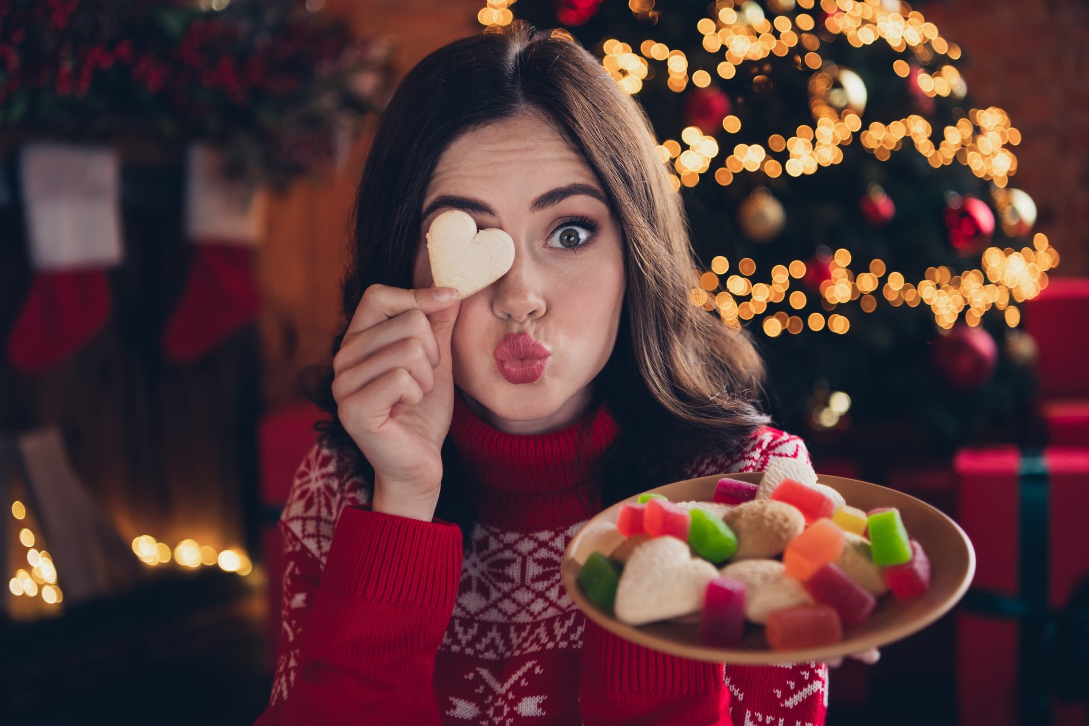 Woman holding cookie over one eye and pouting at the camera.