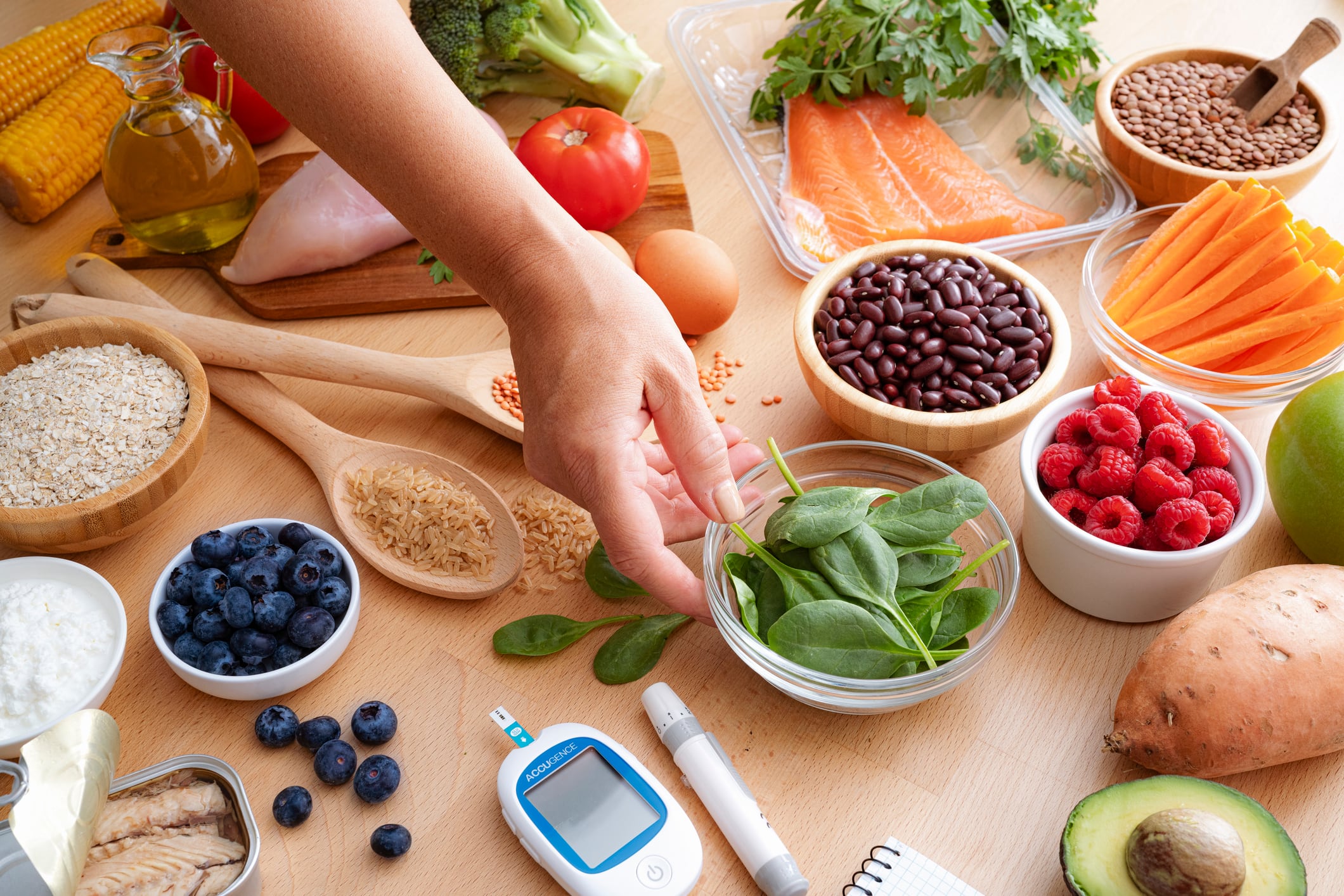 Group of healthy and fresh food recommended for lowering blood glucose levels in diabetic patients. unprocessed foods, plant-based foods and healthy fats. Person holding a spinach leaves bowl