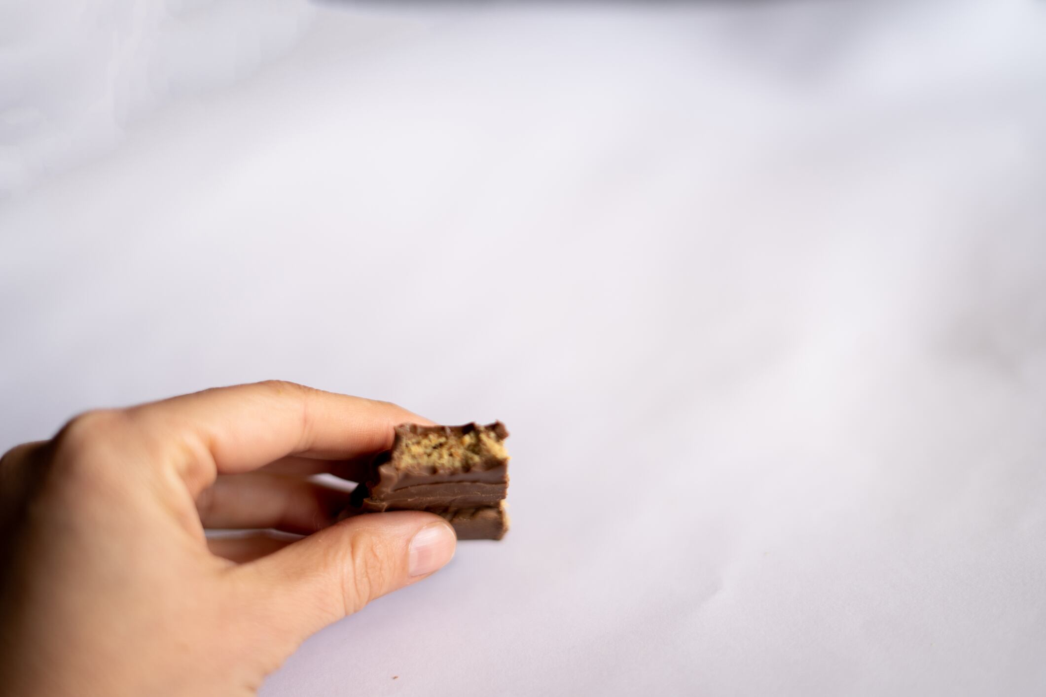 Close up hand holding piece chocolate isolated on white background
