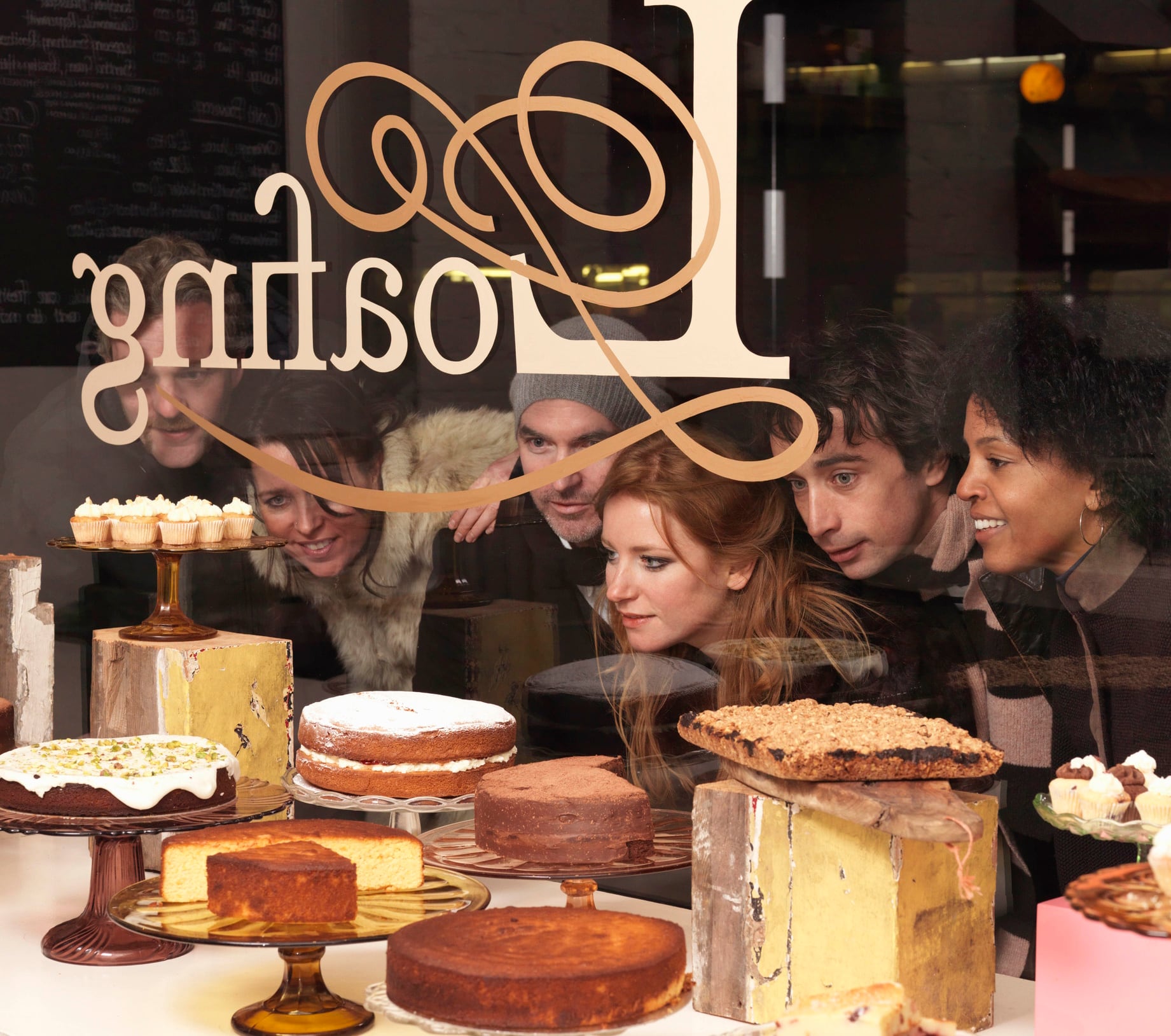 Group of people looking at baked goods in bakery window