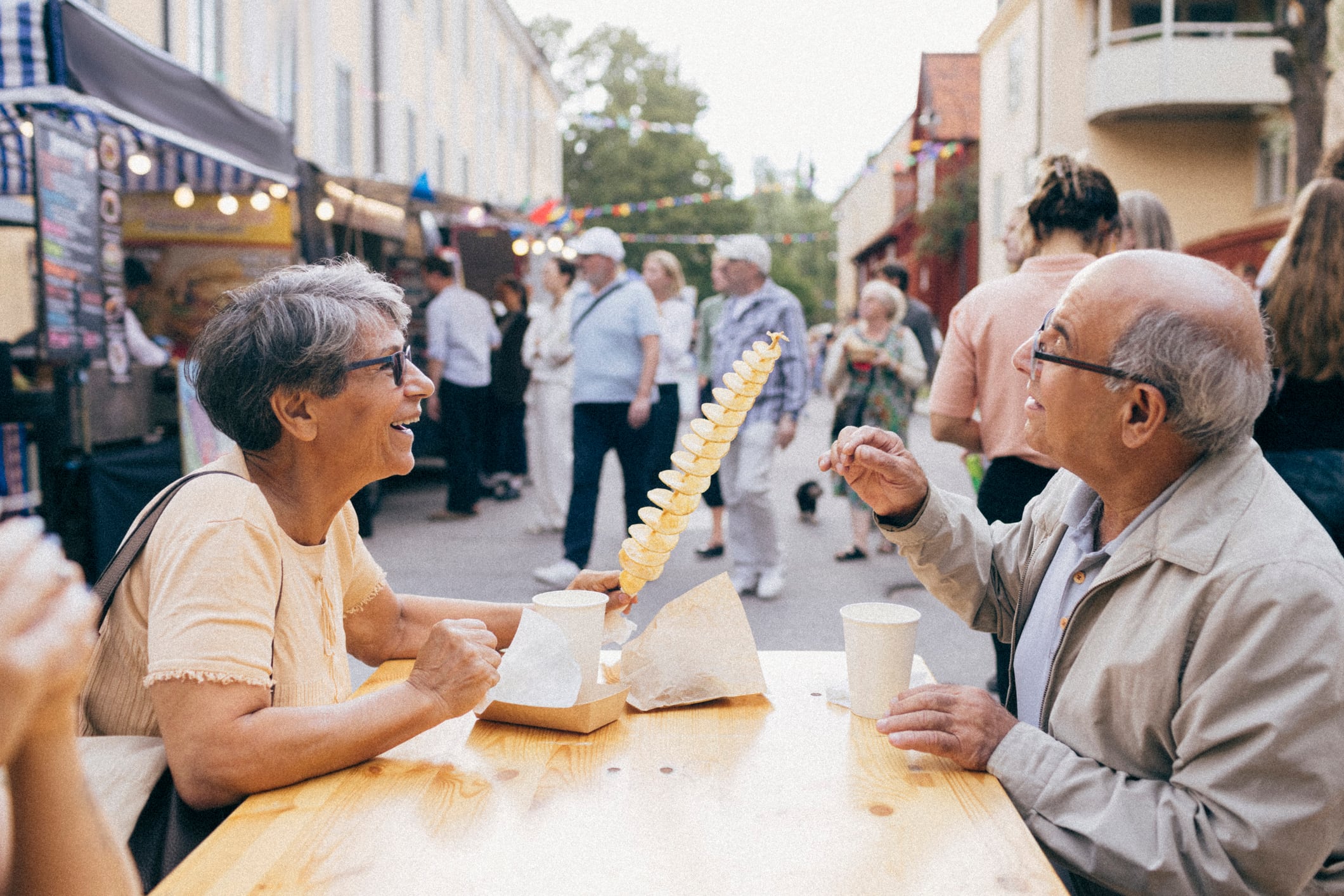 Two older people seated at a table, about to eat tornado potatoes