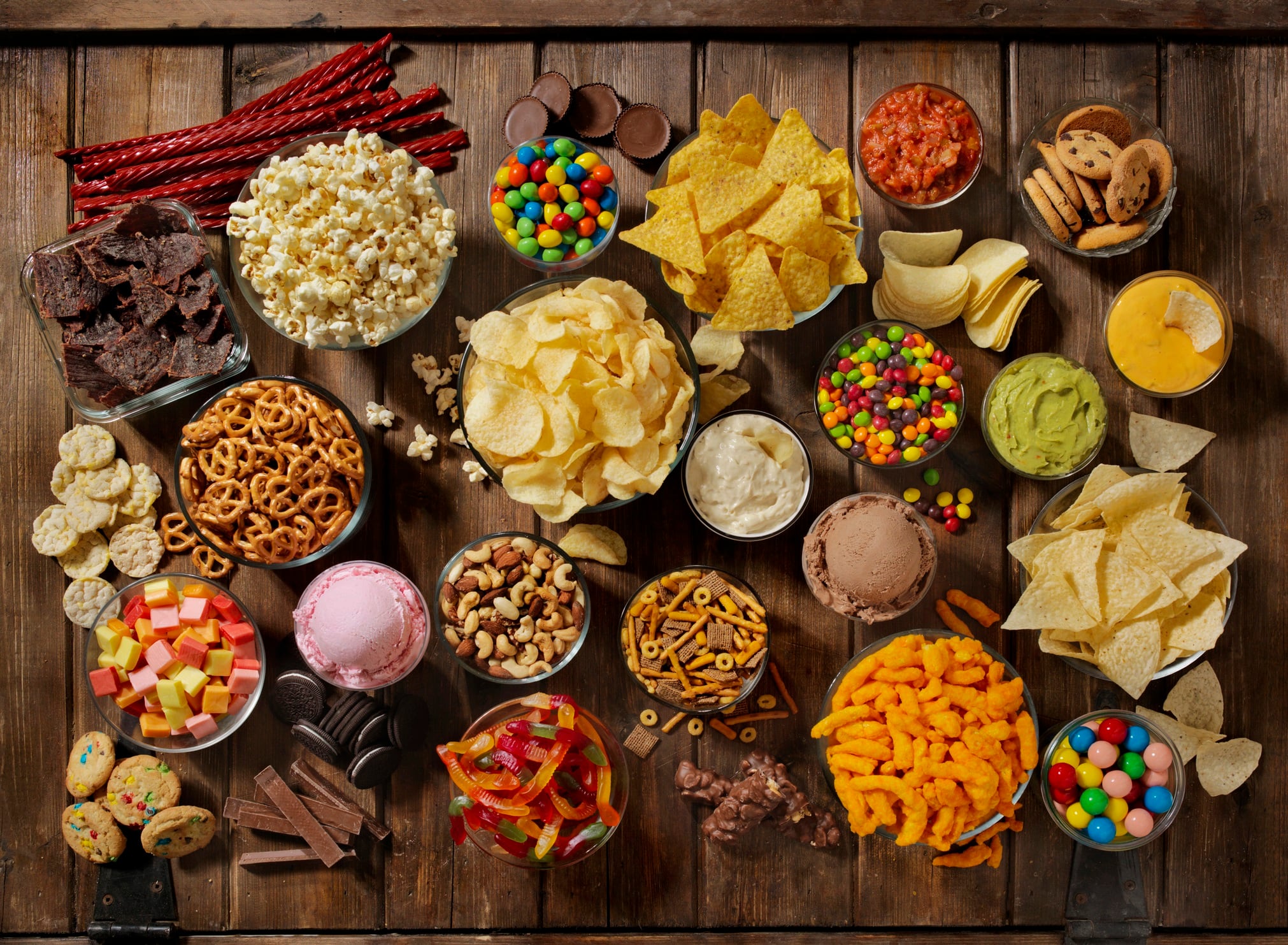Wooden table with bowls of sweets, crisps, biscuits and dips on.