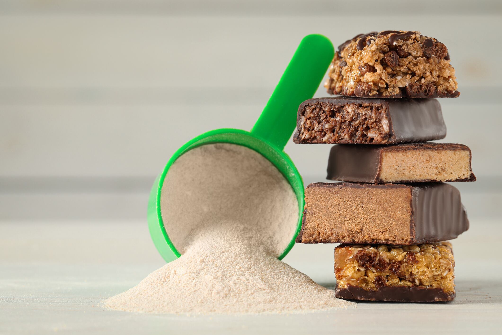 Different tasty energy bars and protein powder on white table, closeup - stock photo Liudmila Chernetska GettyImages