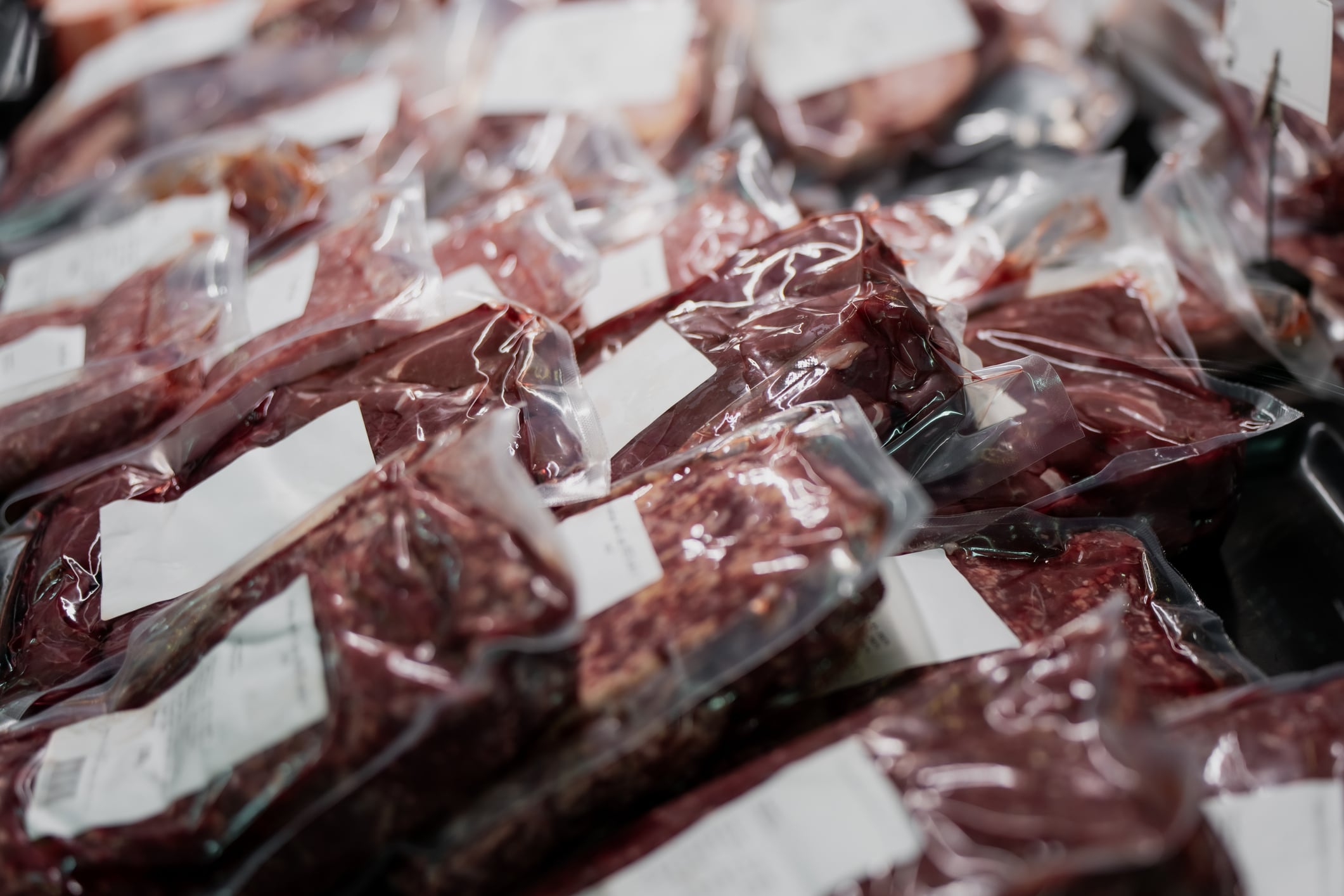 Fresh raw beef steaks vacuum packed for preservation in butcher shop, focused on meat processing, food supply chain, and retail industry