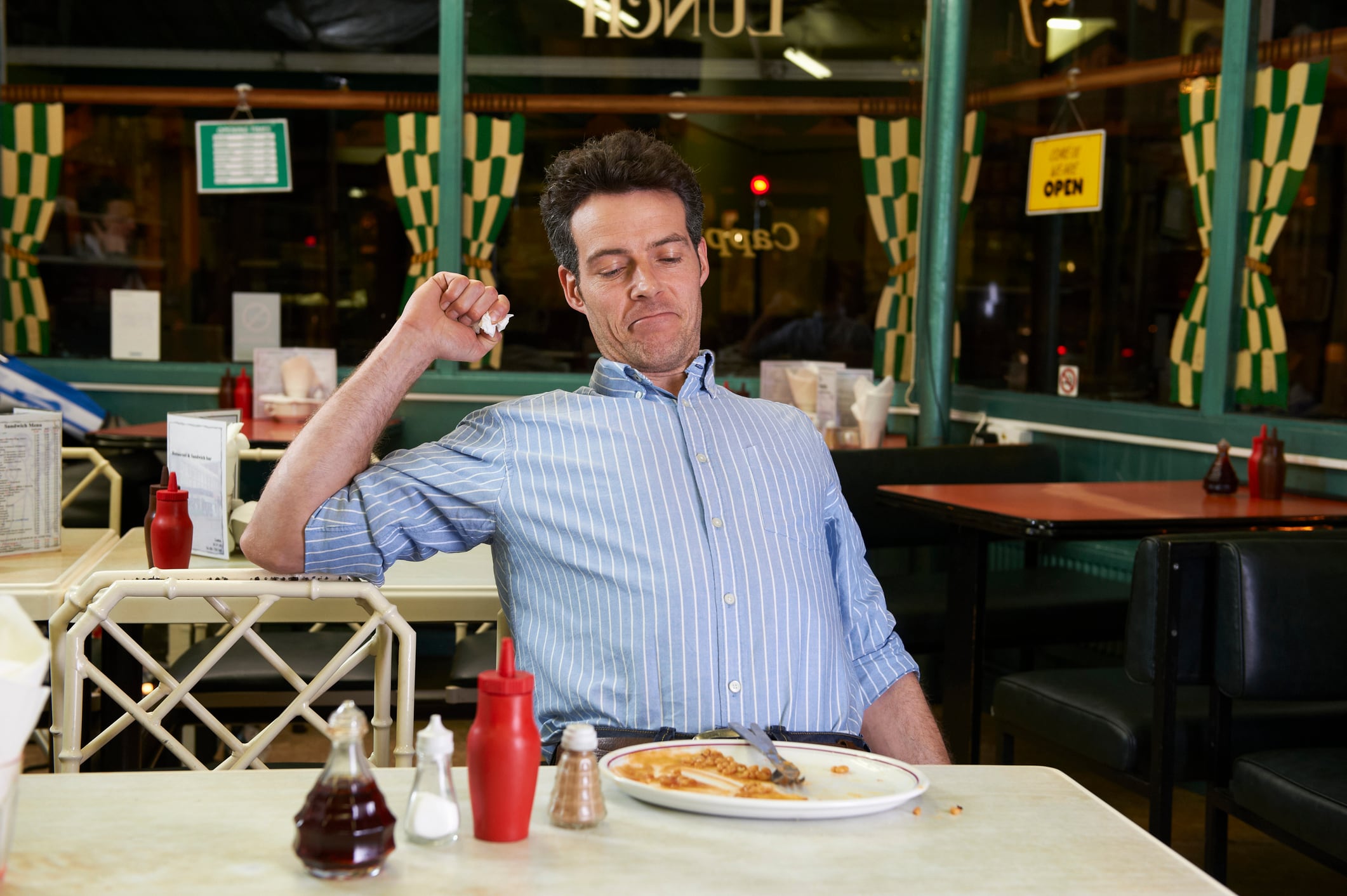 Man in cafe with empty plate, feeling full