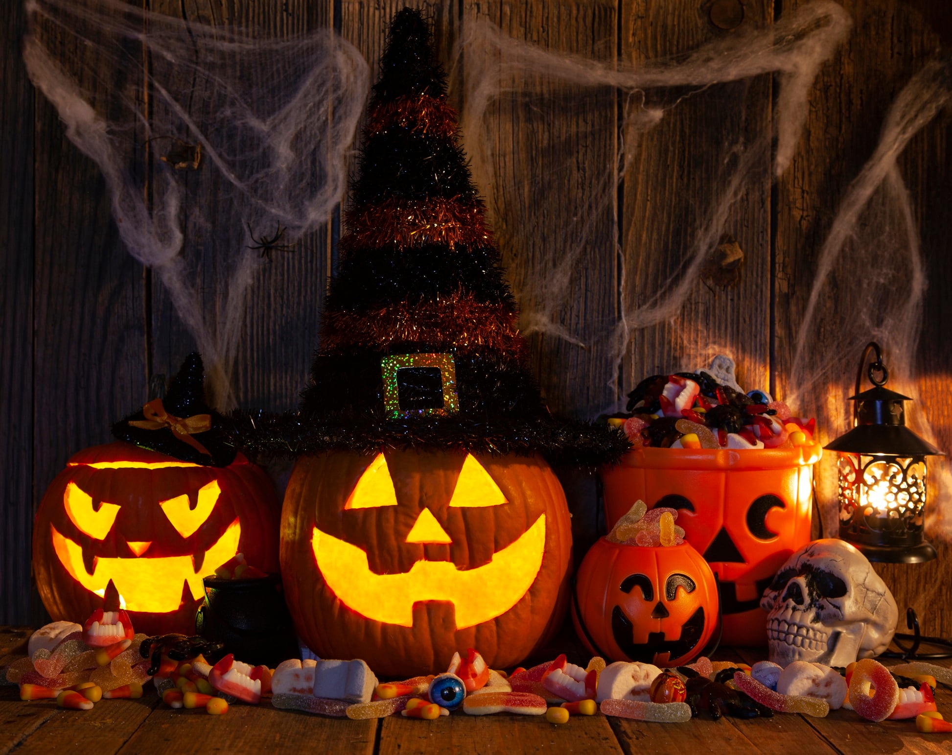 Halloween pumpkins with pile of candies on rustic wooden background.
