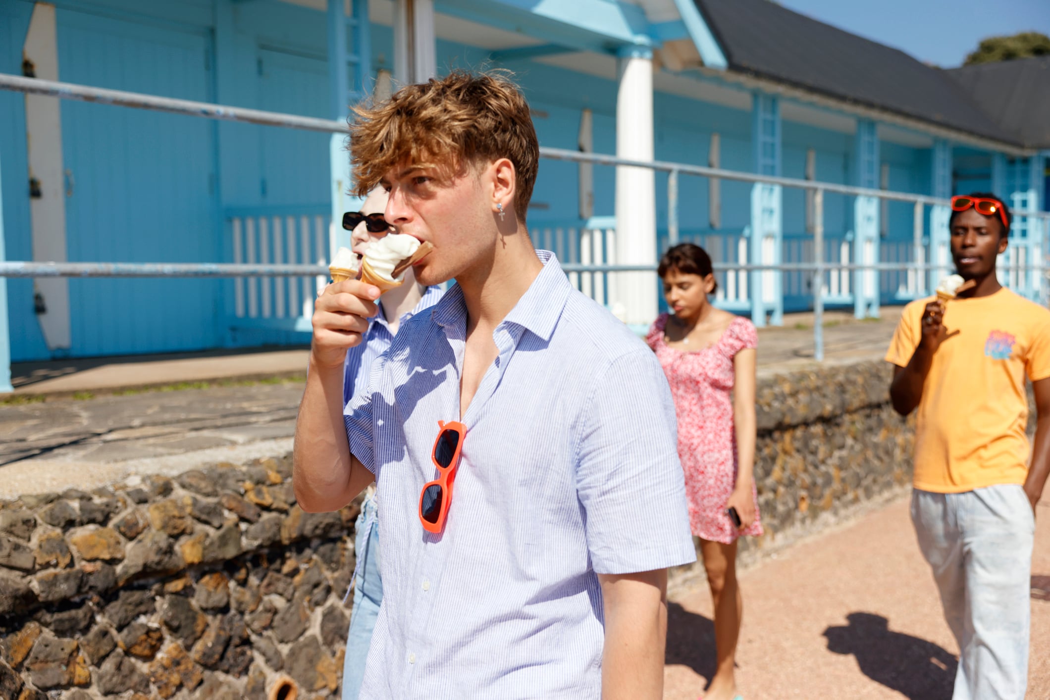 A young man eating an ice cream with his friends at the seaside - getting away from it all