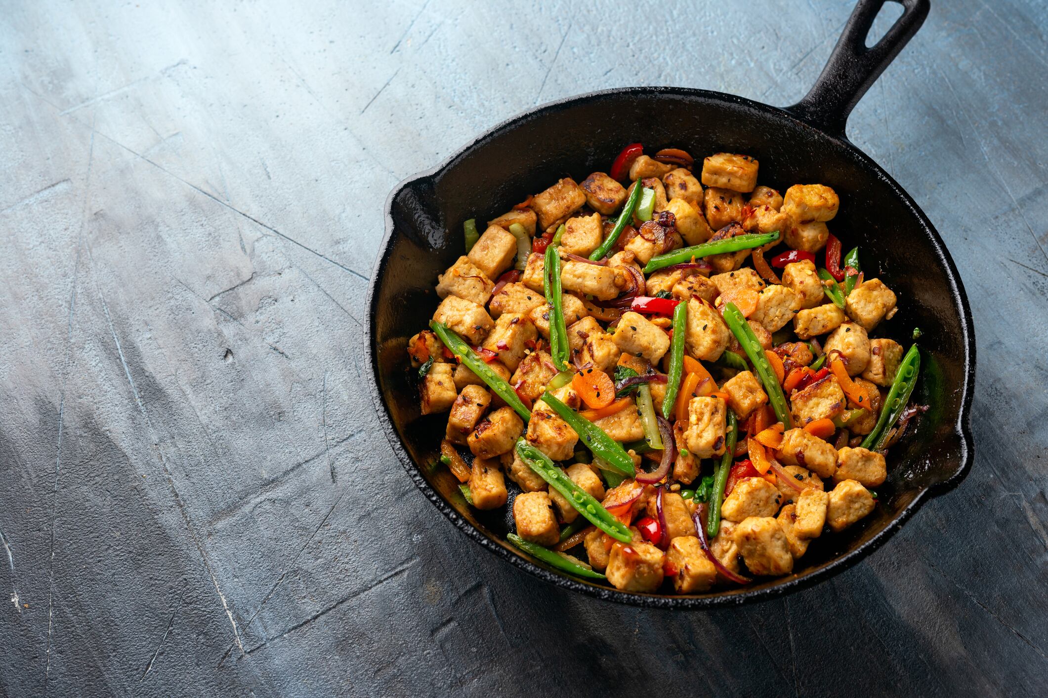 Vegetarian meat free mycoprotein pieces vegetable stir fry served in cast iron skillet frying pan.