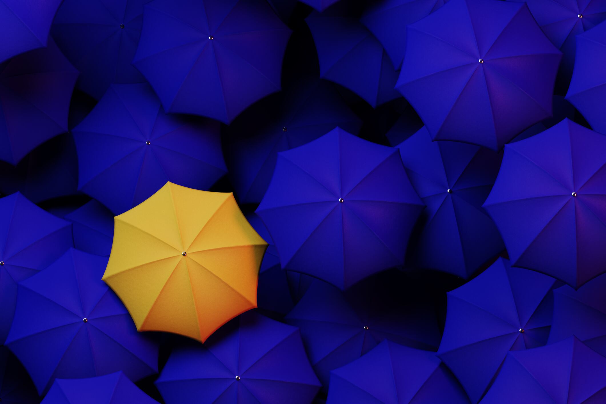 Large group of blue umbrellas with a single yellow umbrella standing out