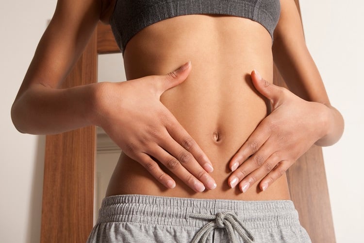 Image of woman with hands on stomach - used to illustrate gut health.
